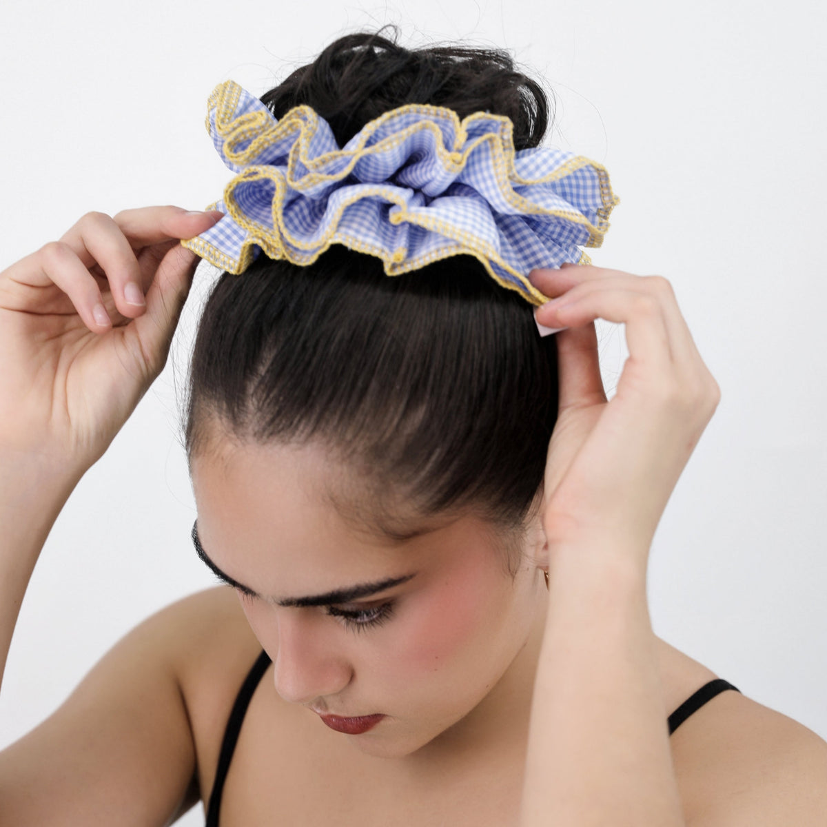 Woman wearing a Luna Wave blue check scrunchie on her hair against a white background