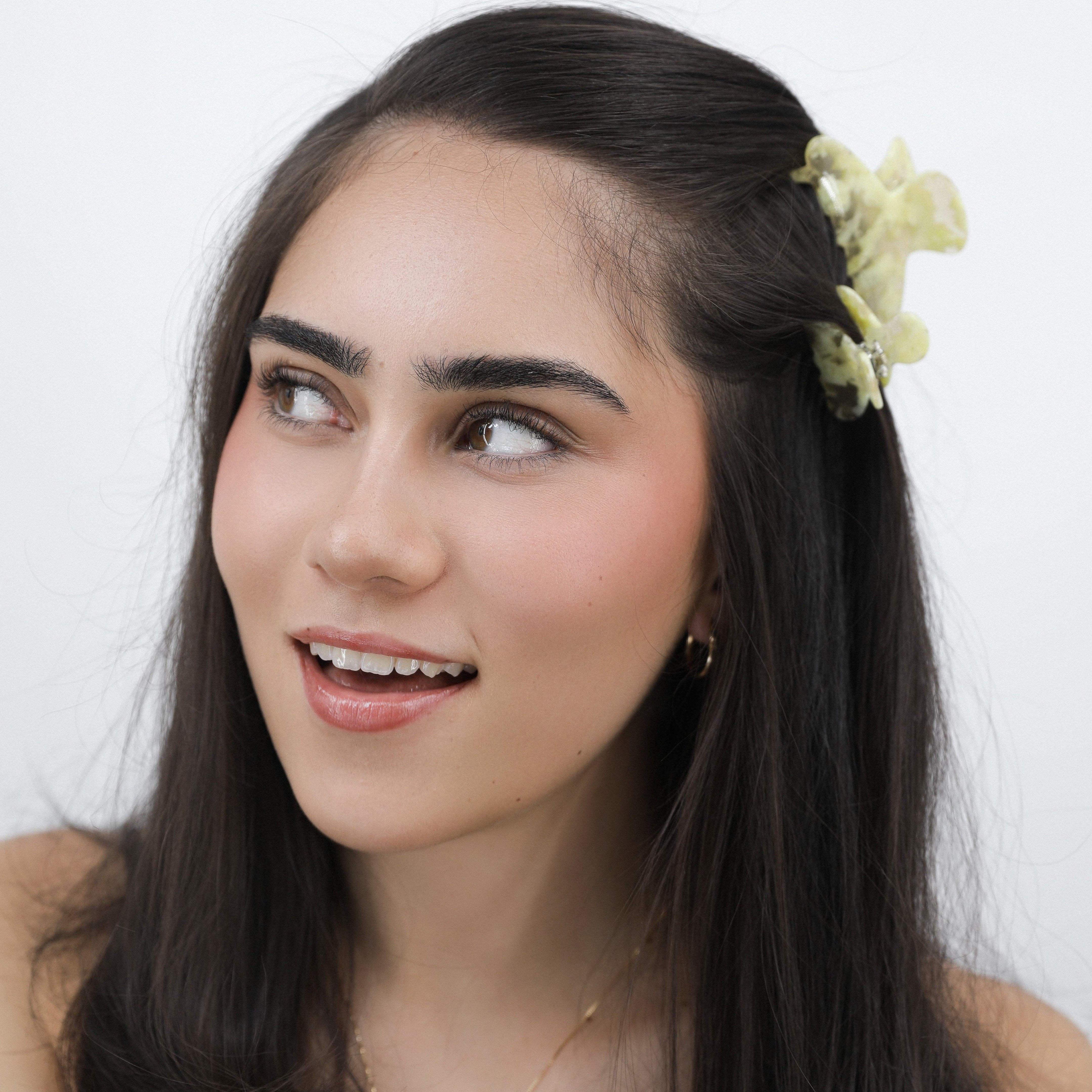 Lady with long dark hair and a Luna Wave yellow butter flora hair claw clip in her hair against a white background