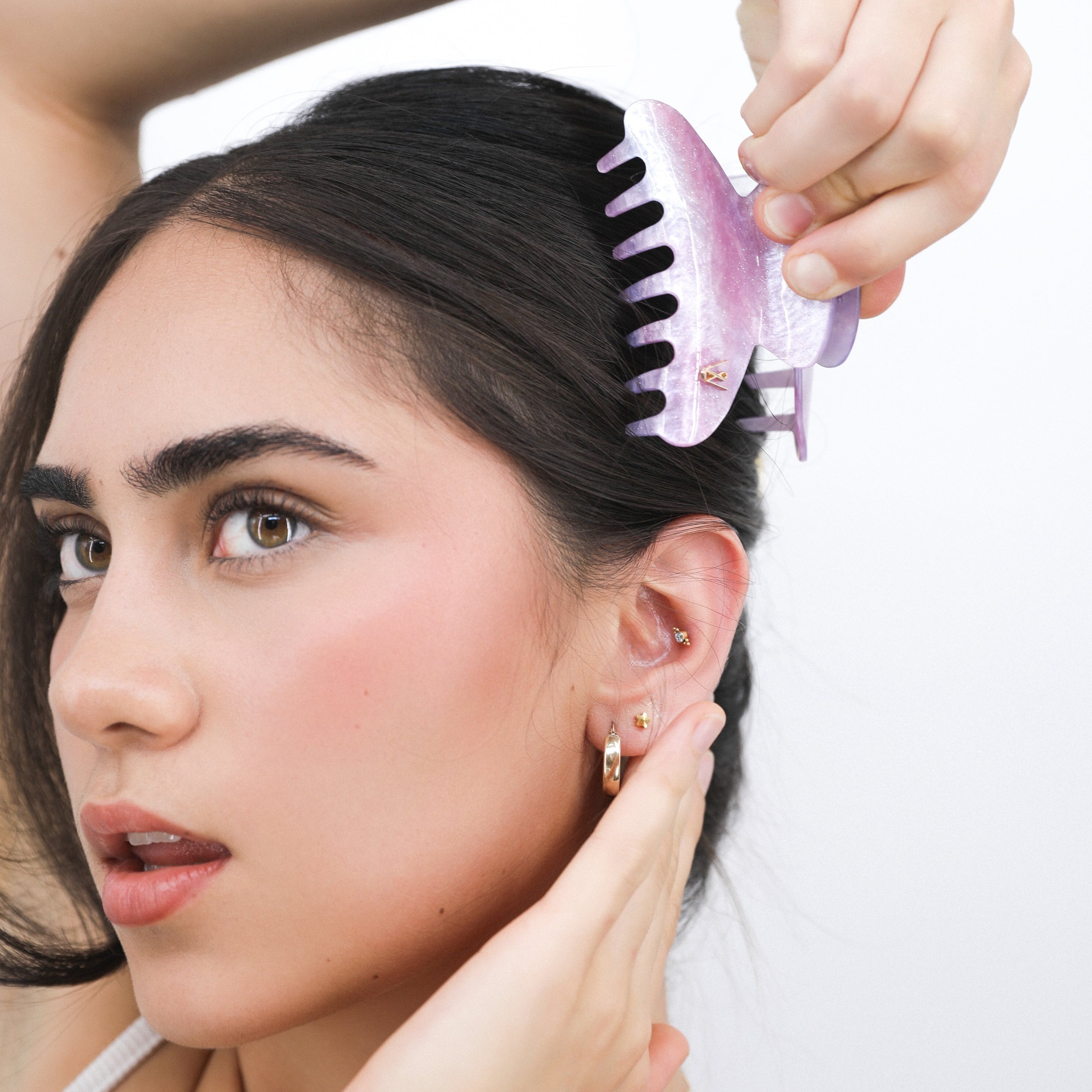 Woman using a Luna Wave pink classic galaxy hair claw clip on her hair against a white background
