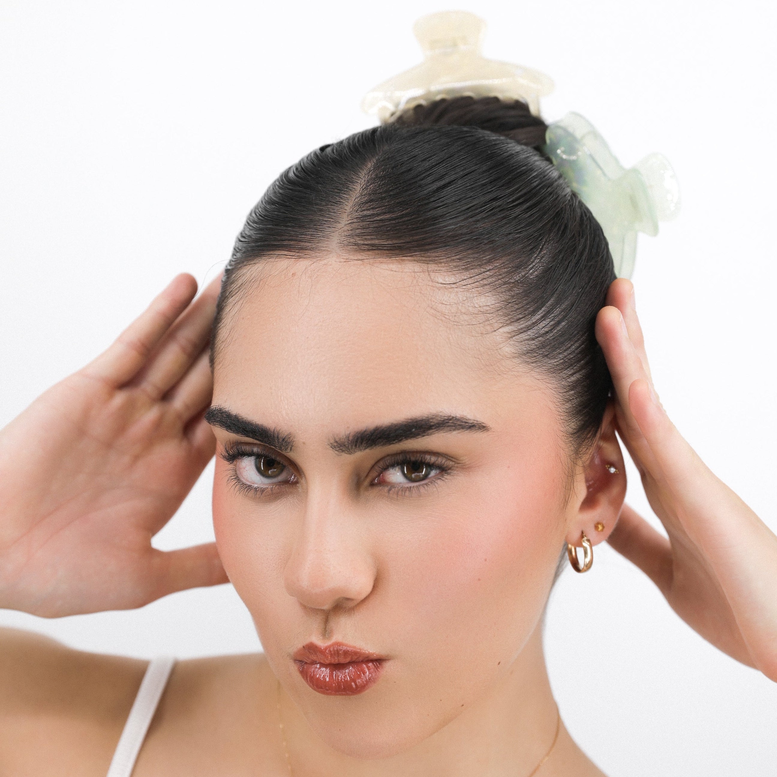Woman with styled hair with Luna Wave initial yellow and green hair claw clips against a white background