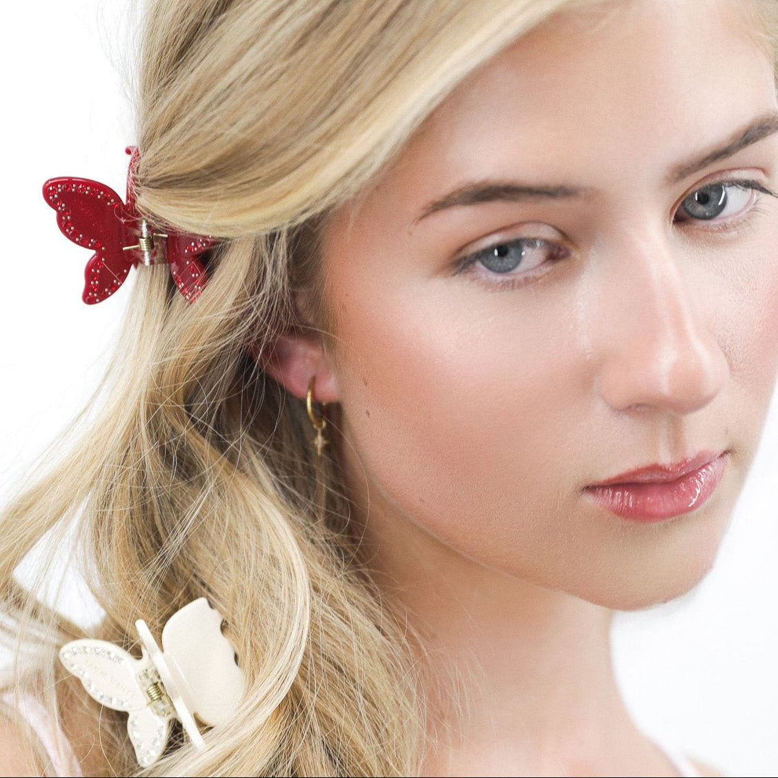 Lady wearing Luna Wave ruby red and luna white butterfly hair claw clips with a white background.