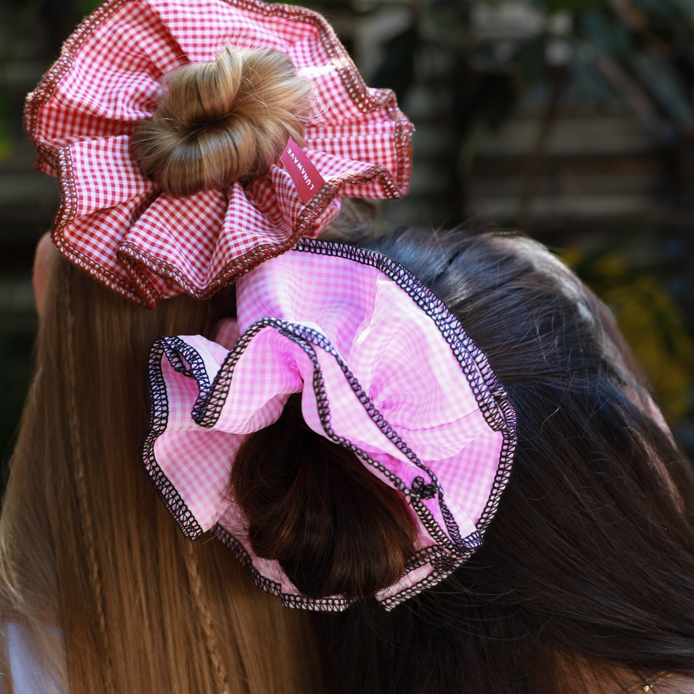 Person with decorative pink hair accessories on a blurred outdoor background