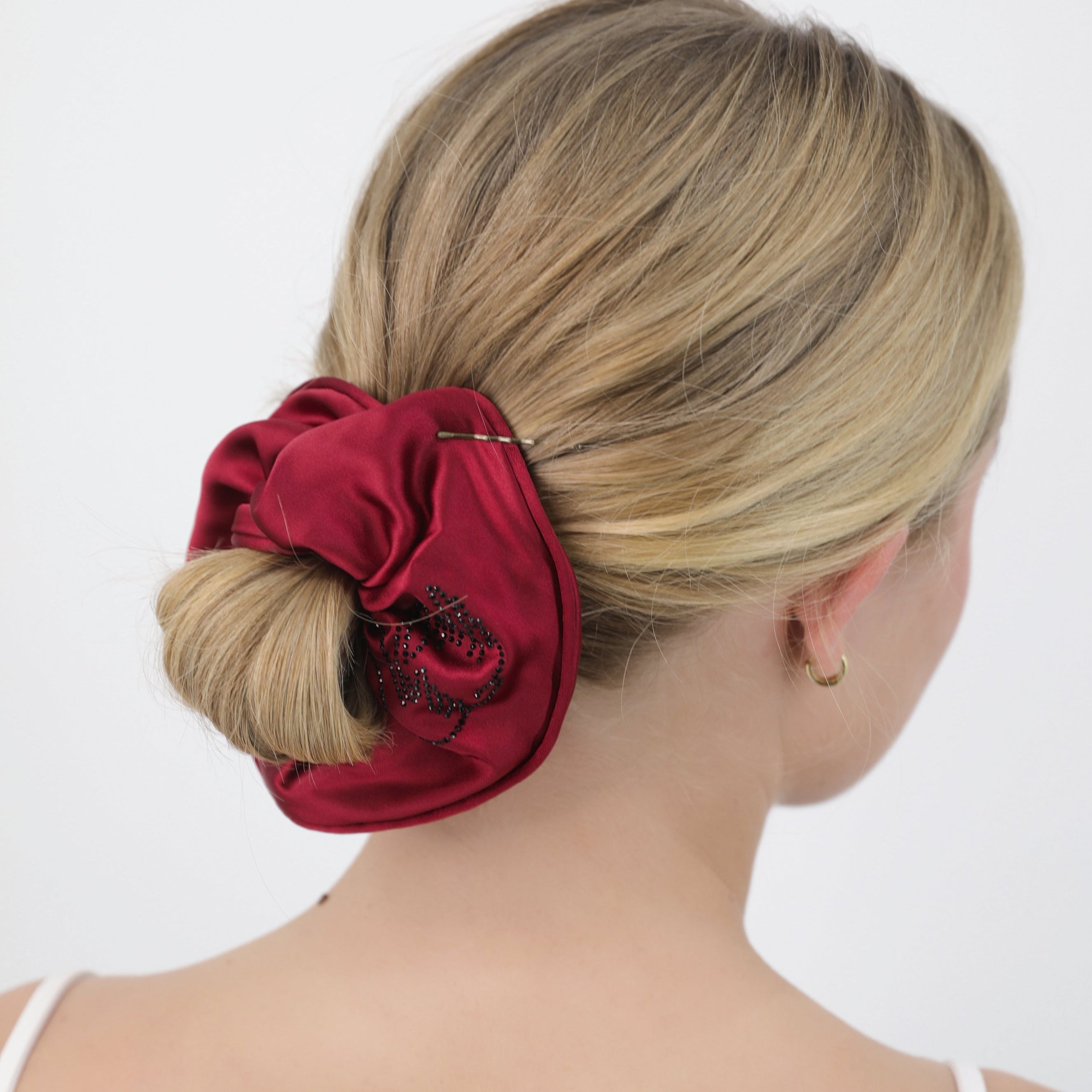 Woman with a Luna Wave red odette scrunchie in her hair on a white background