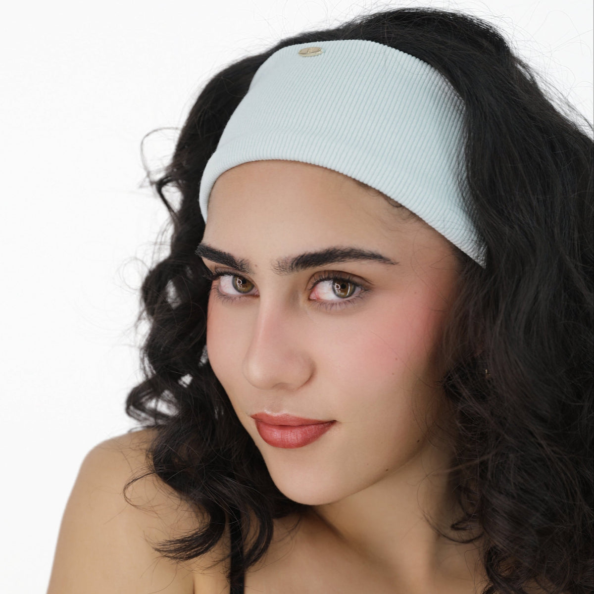 Woman wearing a Luna Wave blue ice soft hair headband against a white background
