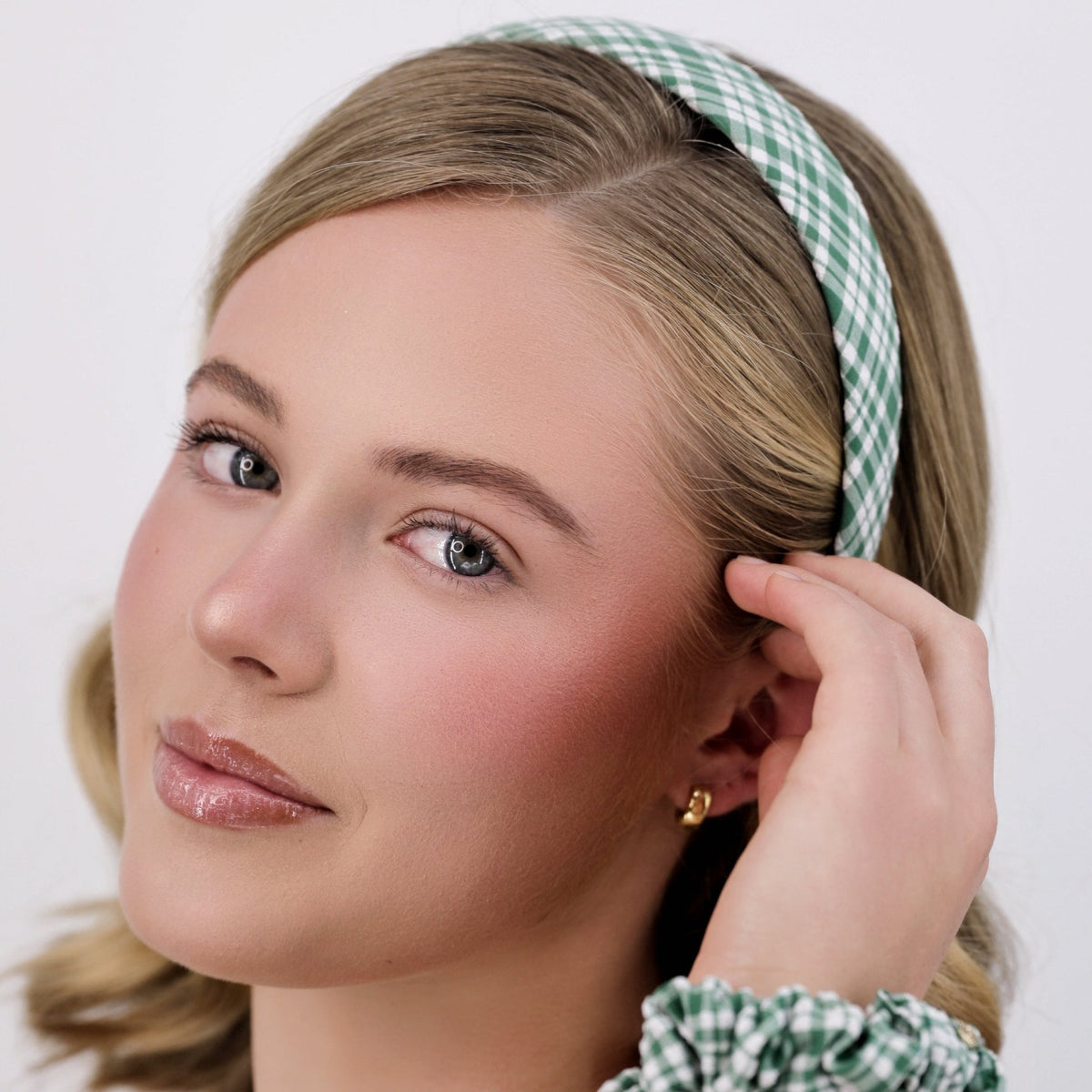 Woman wearing a Luna Wave green meadow gingham headband and scrunchie against a white background