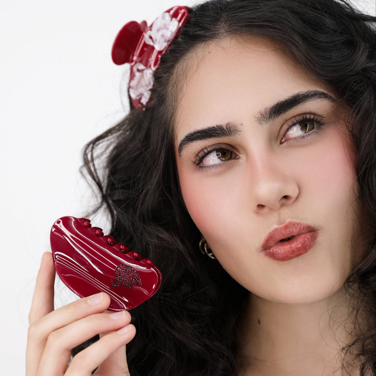 Woman holding a Luna Wave red odette curve hair claw clip against a white background