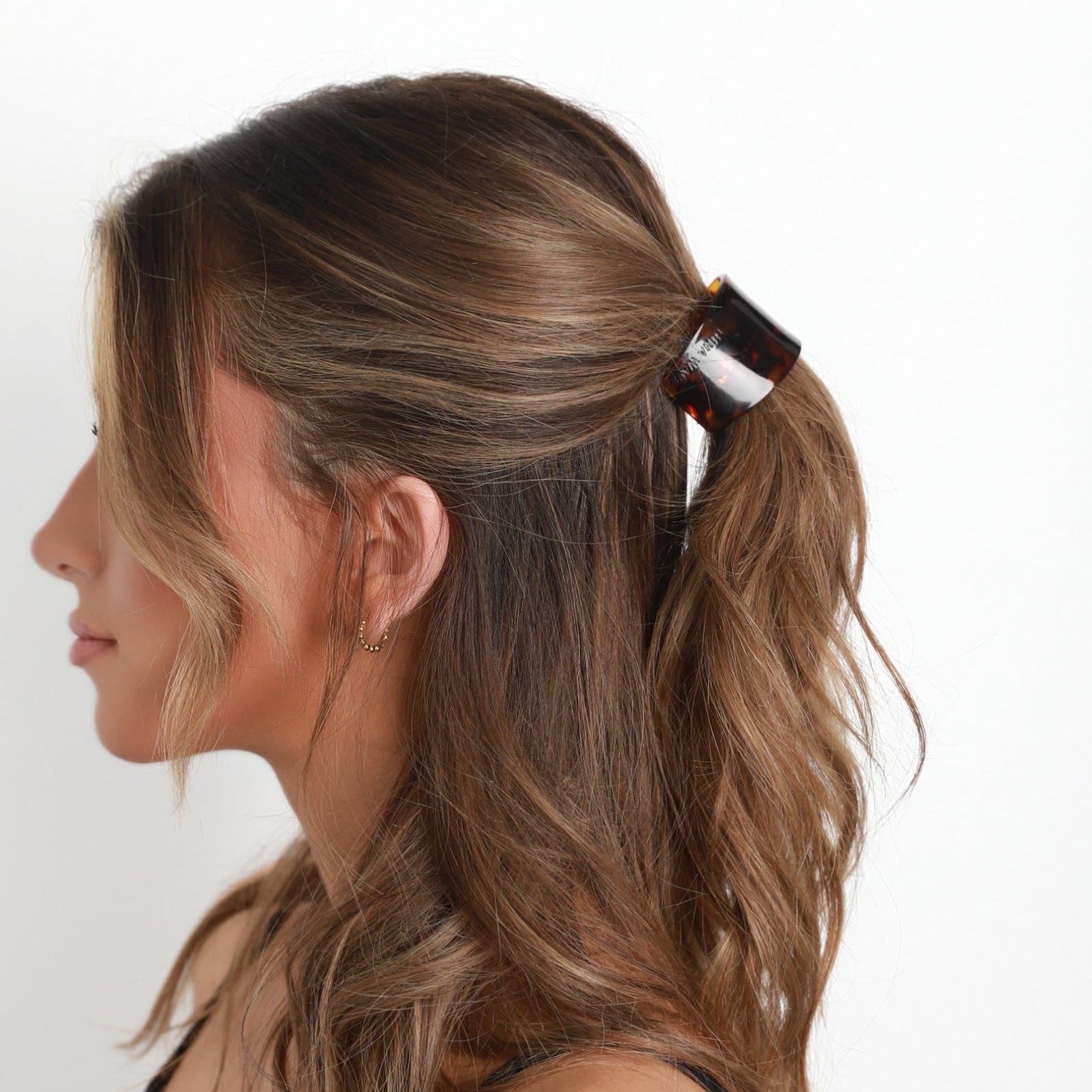 Woman with a ponytail wearing a Luna Wave amber starlet barrette against a white background