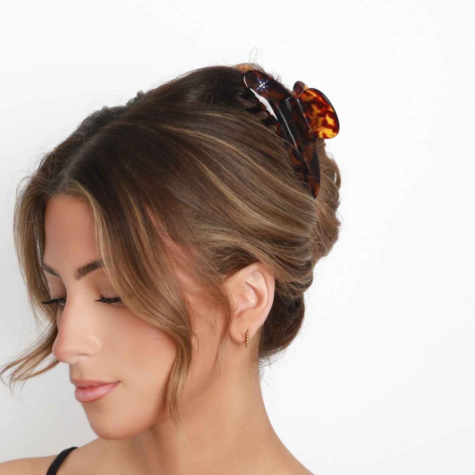 Woman with styled hair wearing a Luna Wave amber starlet large claw clip against a white background