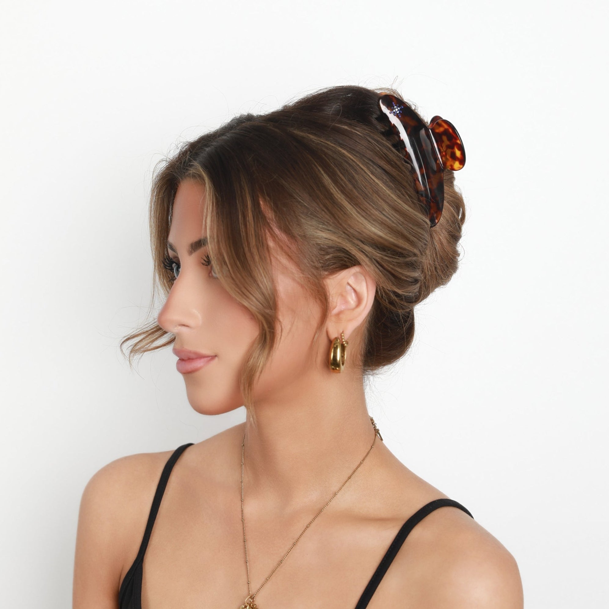 Woman with styled hair and wearing Luna Wave amber starlet large claw clip against a white background