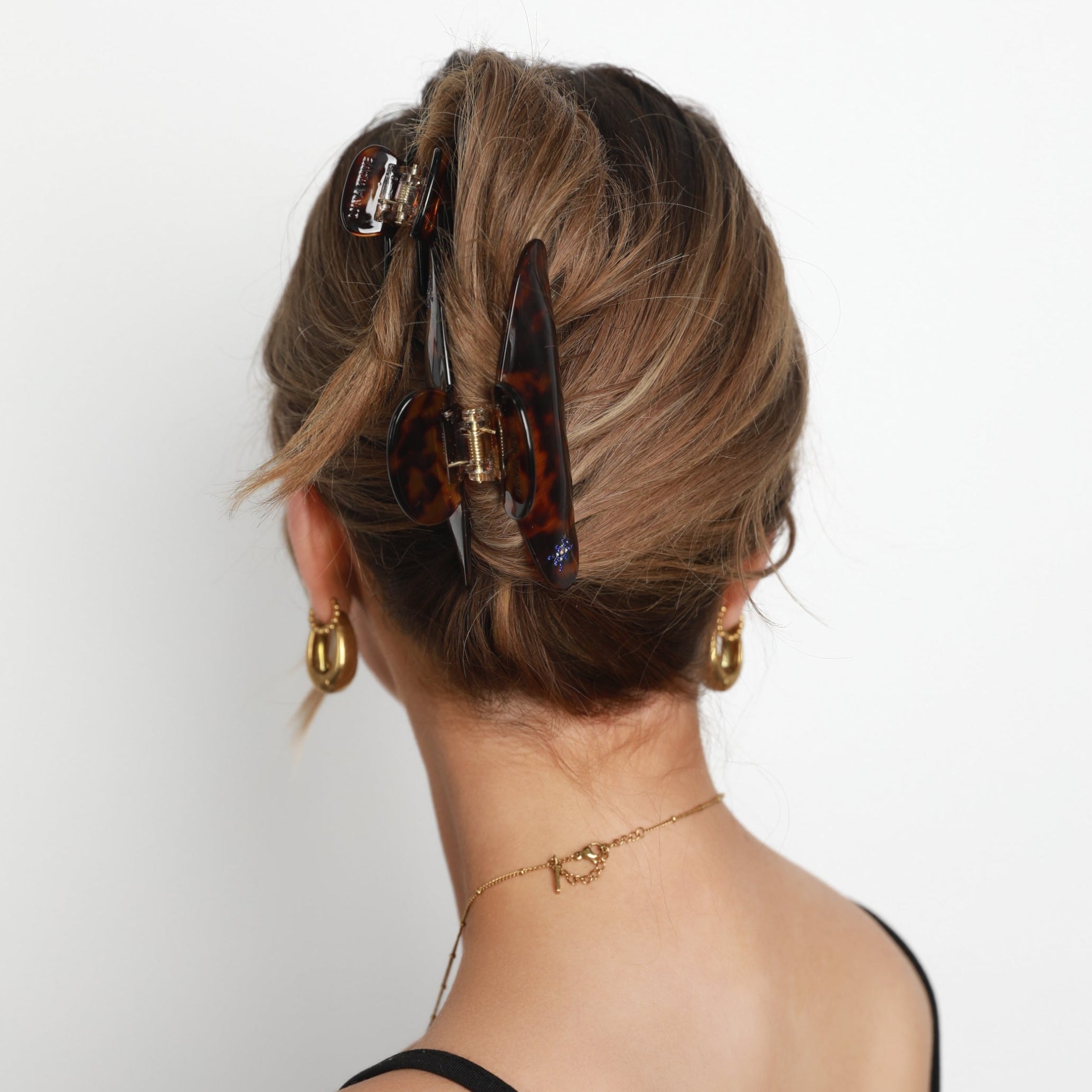 Back view of a person with styled hair and Luna Wave amber starlet claw clips on a white background