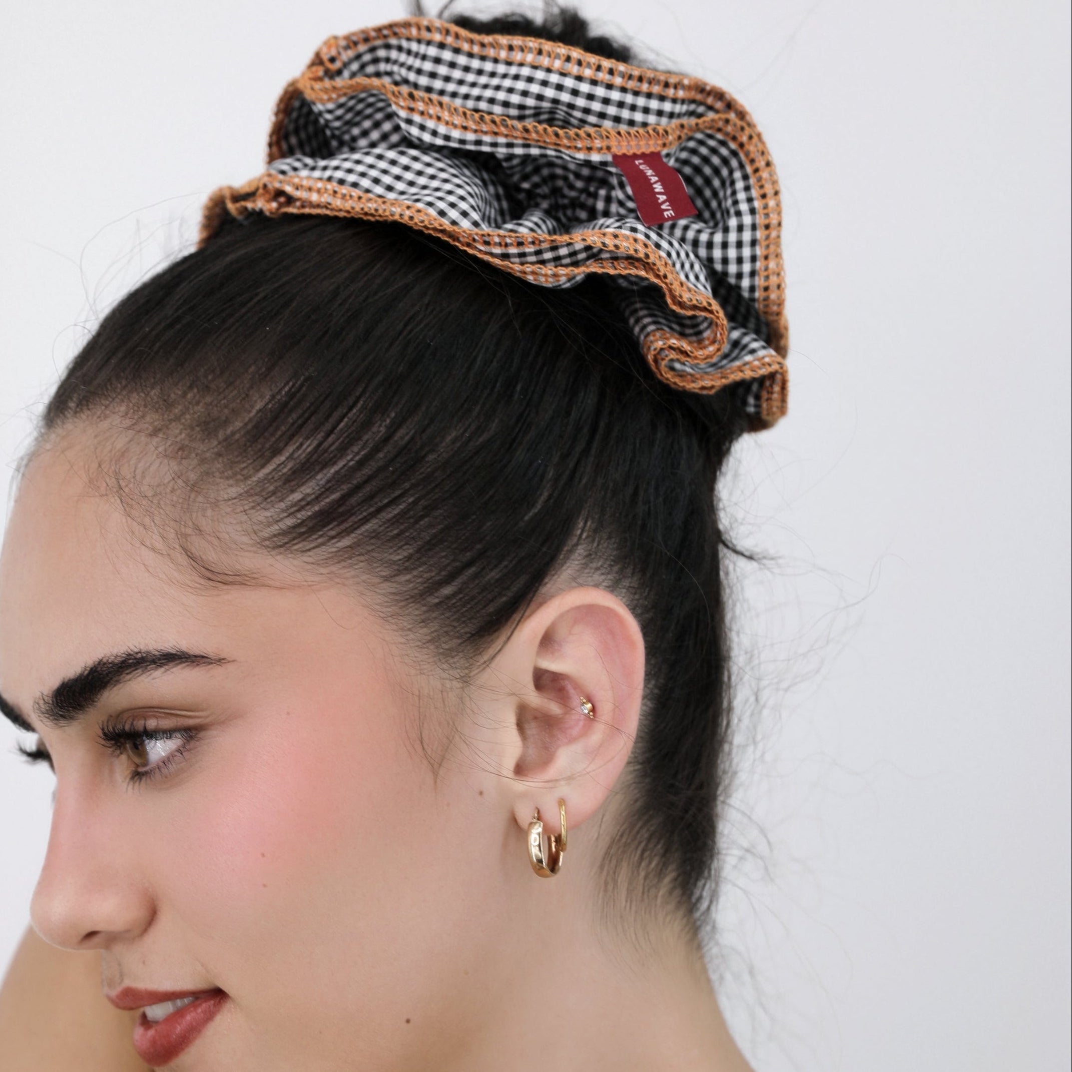 Woman with a Luna Wave black check darling duo scrunchie in her hair against a white background