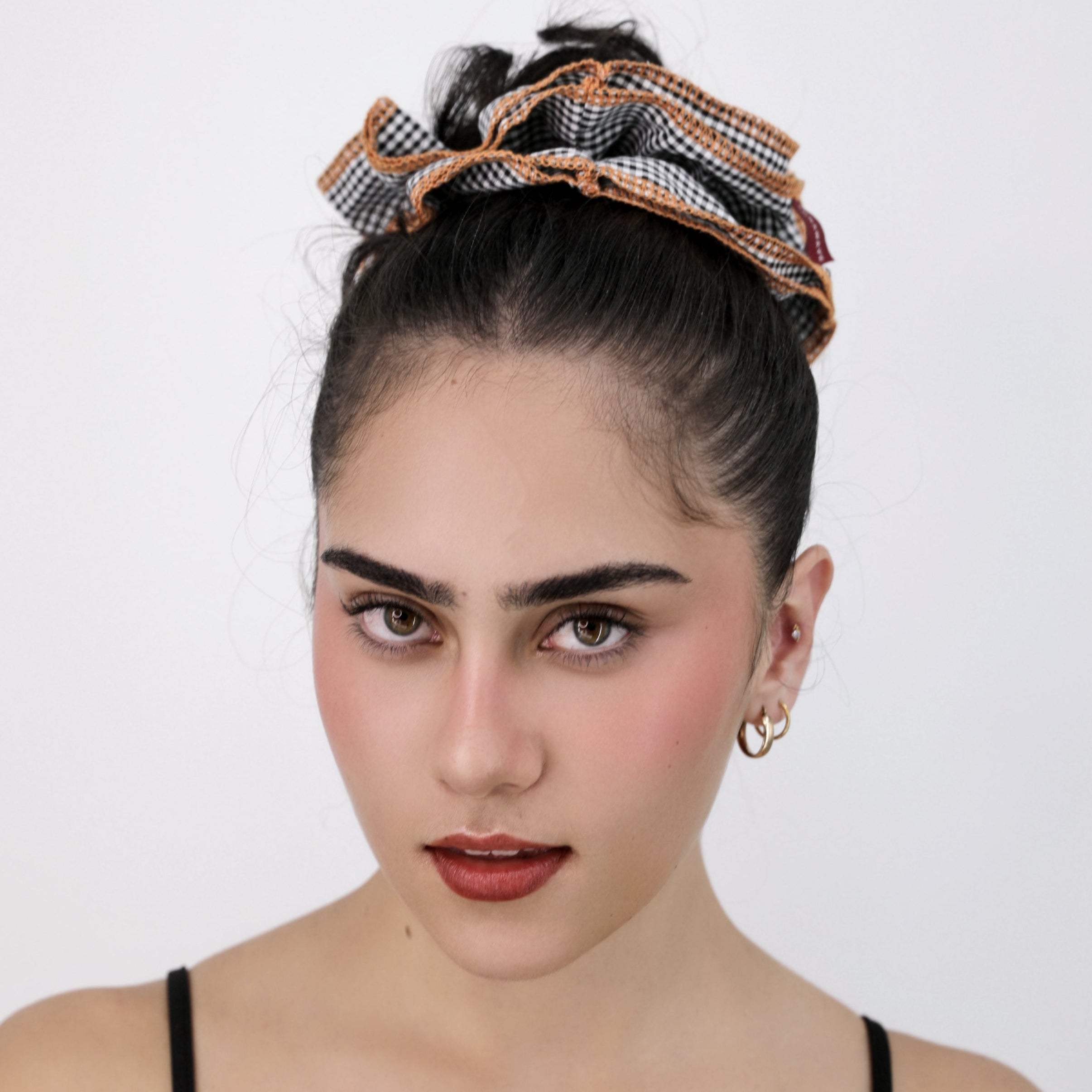 Woman wearing a Luna Wave black check darling duo scrunchie on a white background