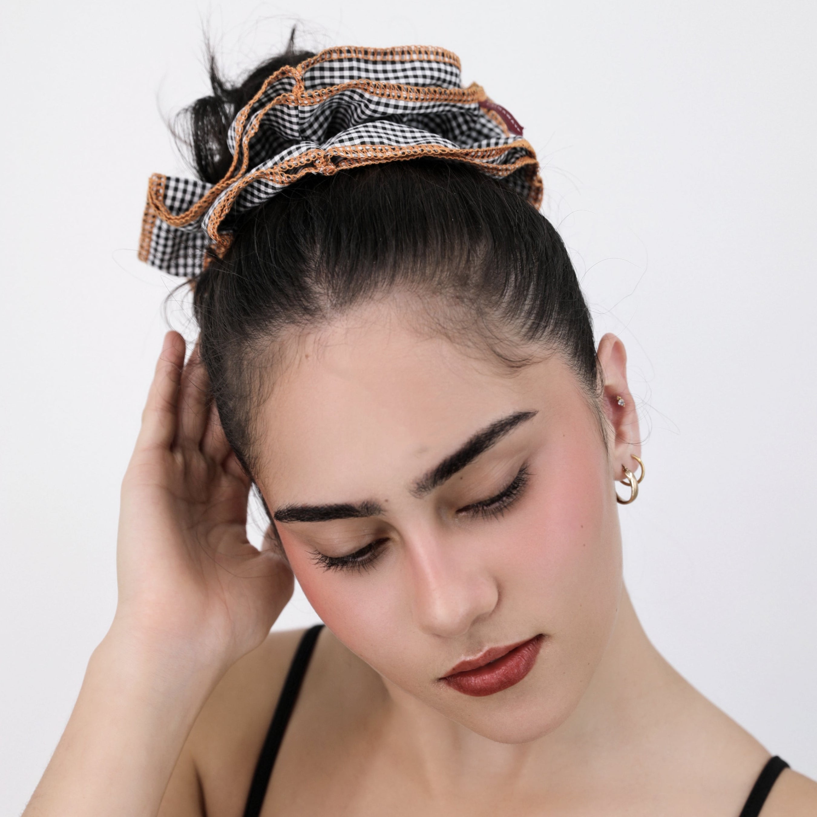 Woman wearing a Luna Wave black checkered darling duo scrunchie against a white background