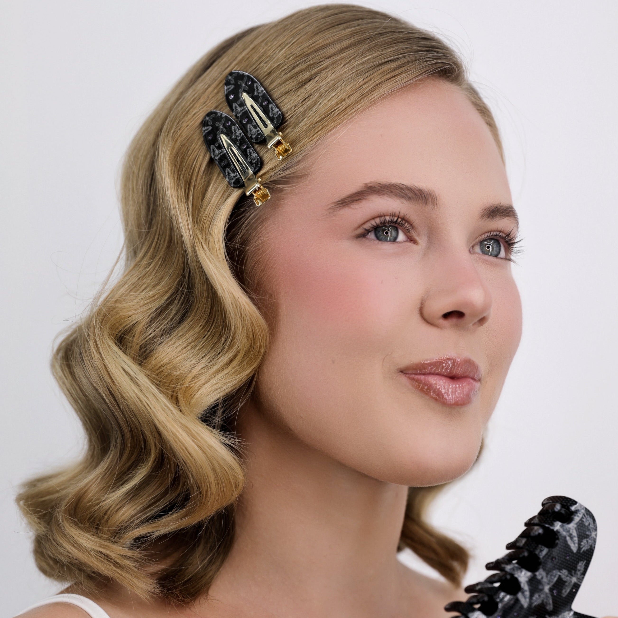 Woman holding a Luna Wave black flatter hair clip with a plain background