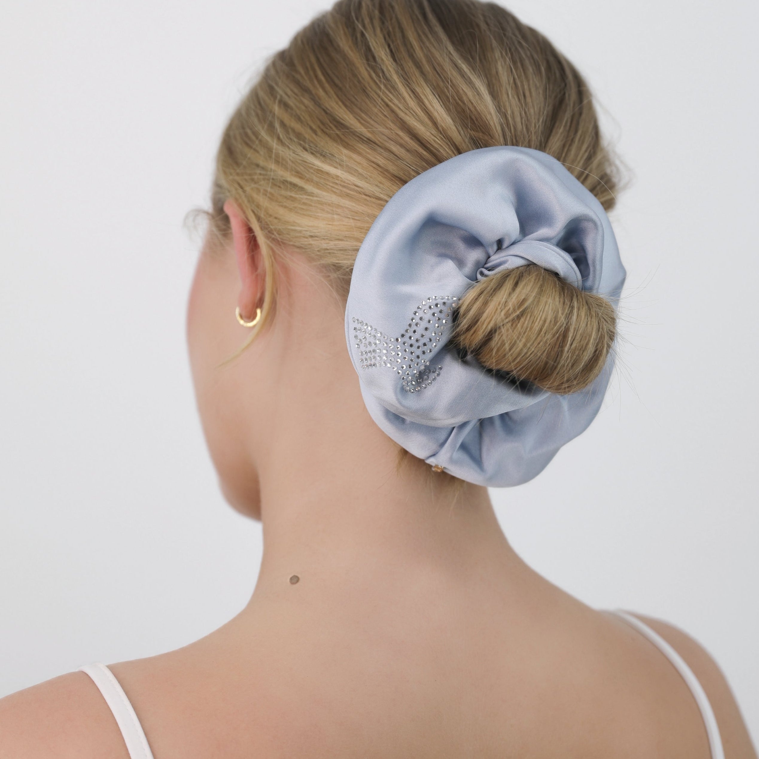 Person wearing a Luna Wave blue bubles scrunchie in their hair against a white background