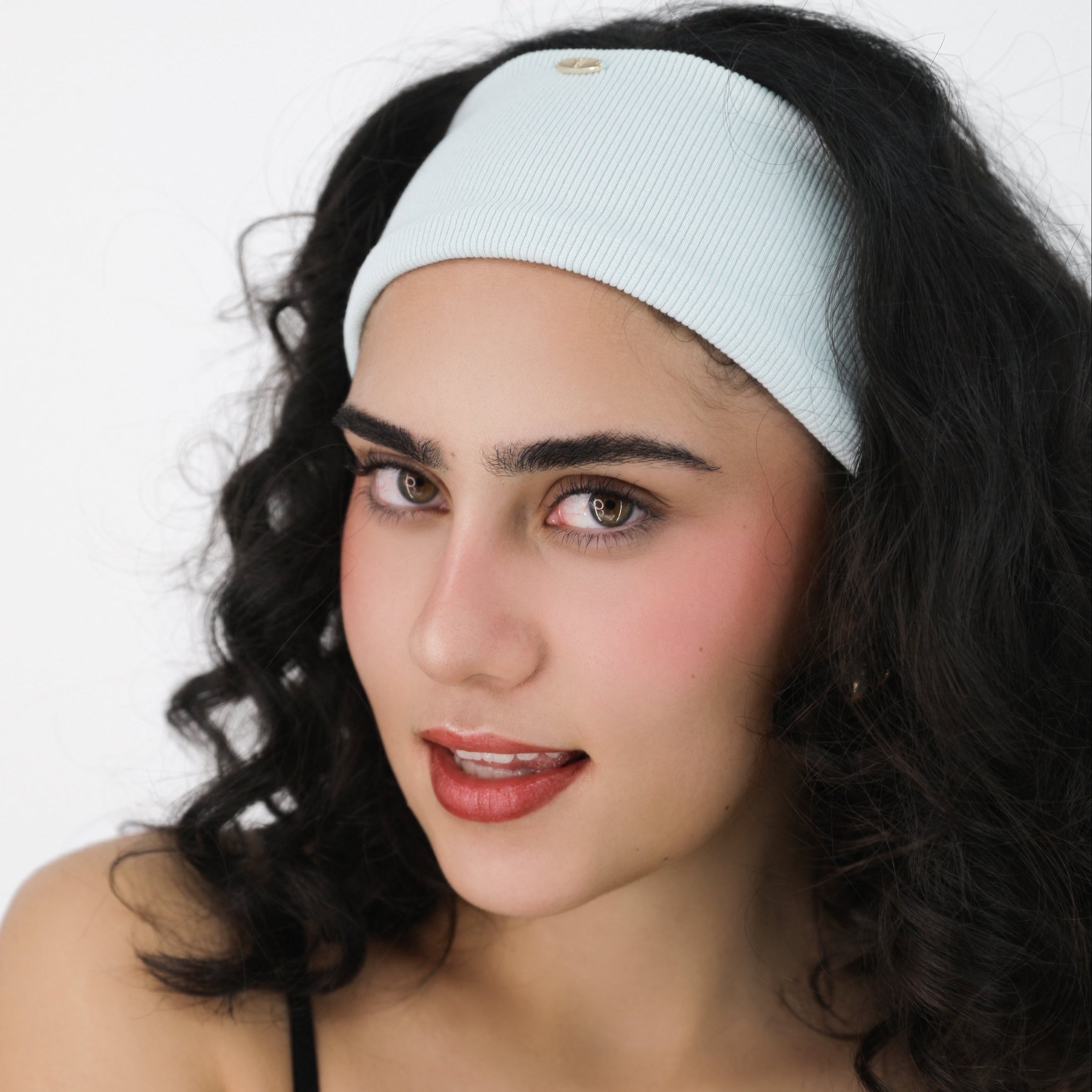 Woman wearing a Luna Wave light blue ice soft hair headband against a white background