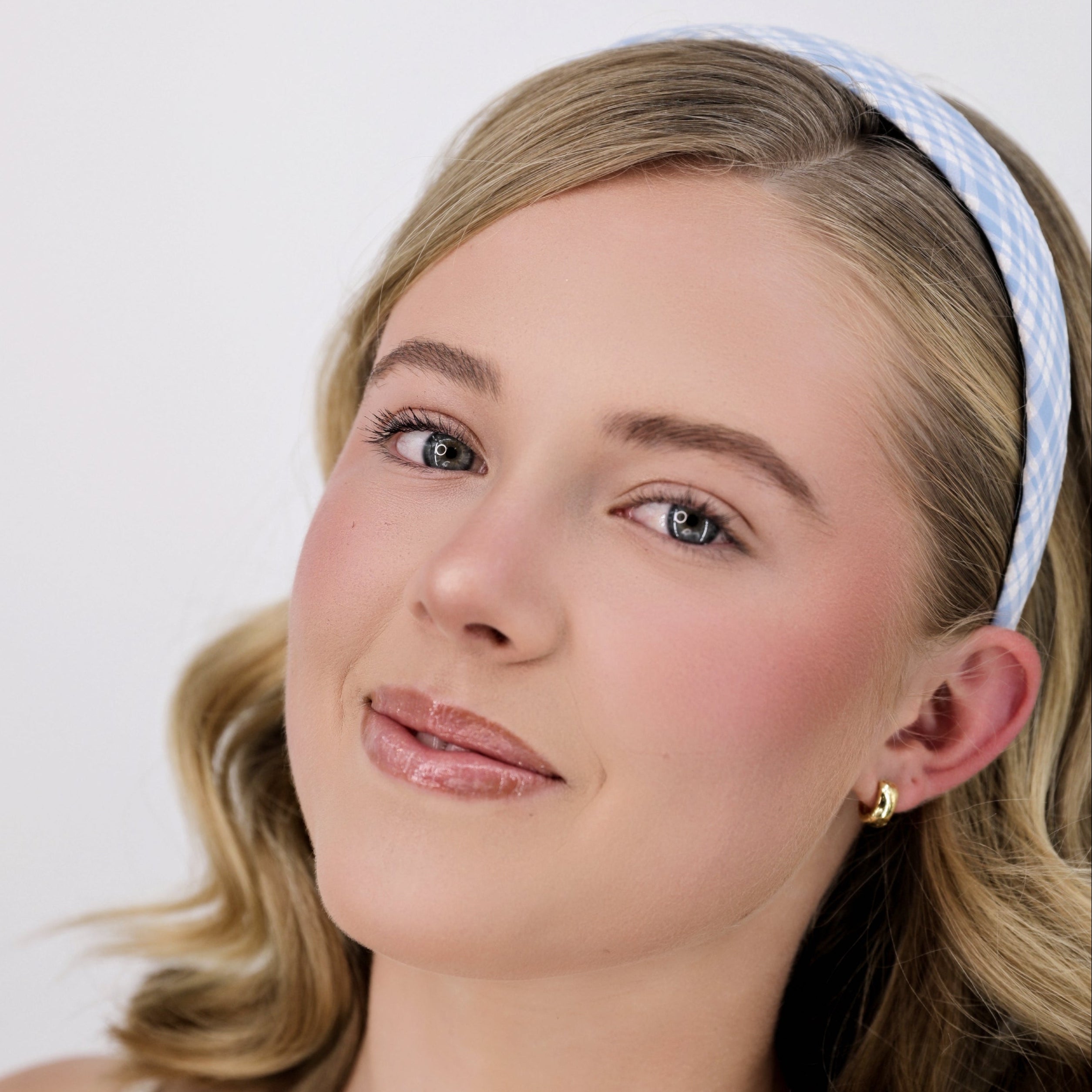 Woman wearing a Luna Wave blue sky gingham headband against a plain background