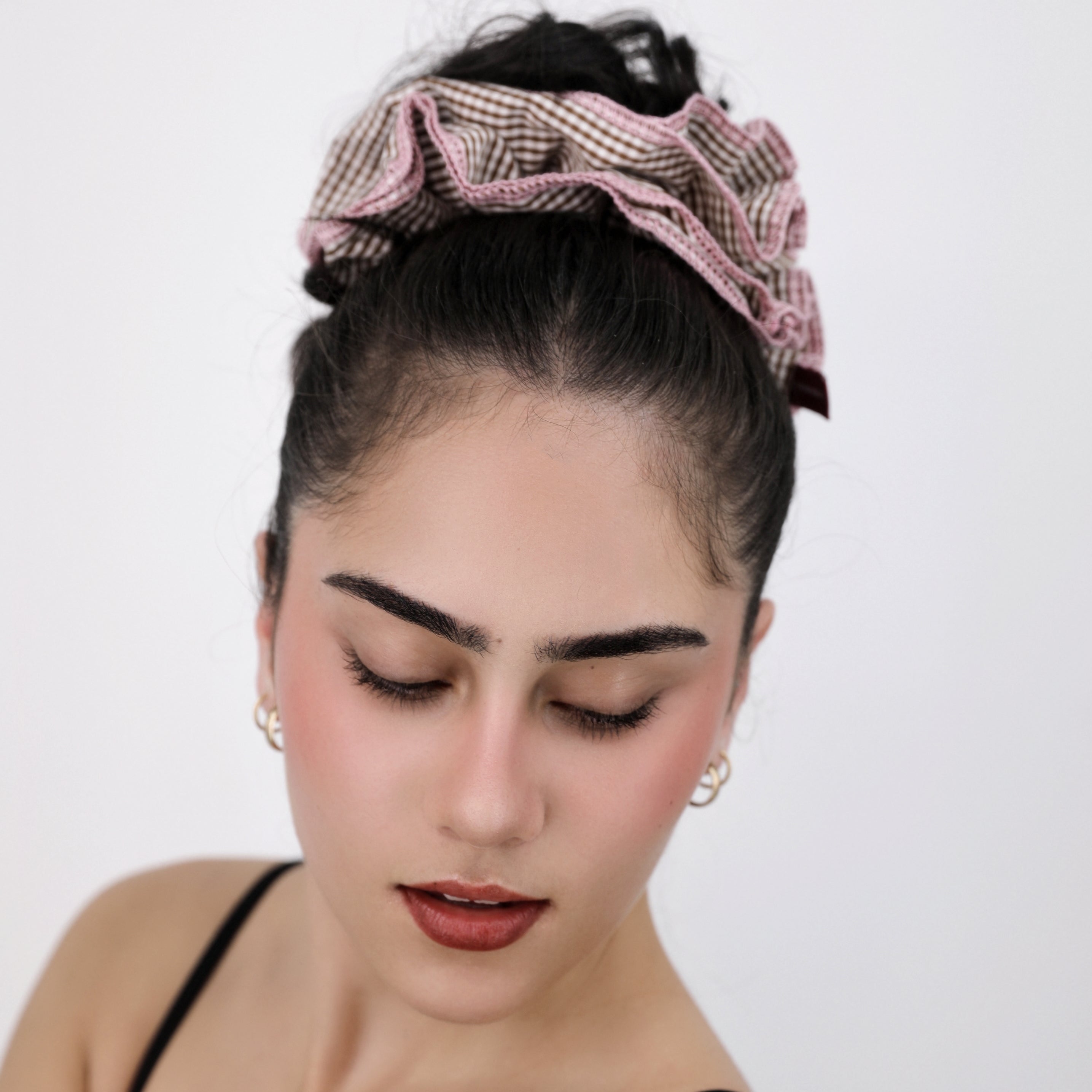 Woman wearing a Luna Wave brown check scrunchie with decorative elements on a white background