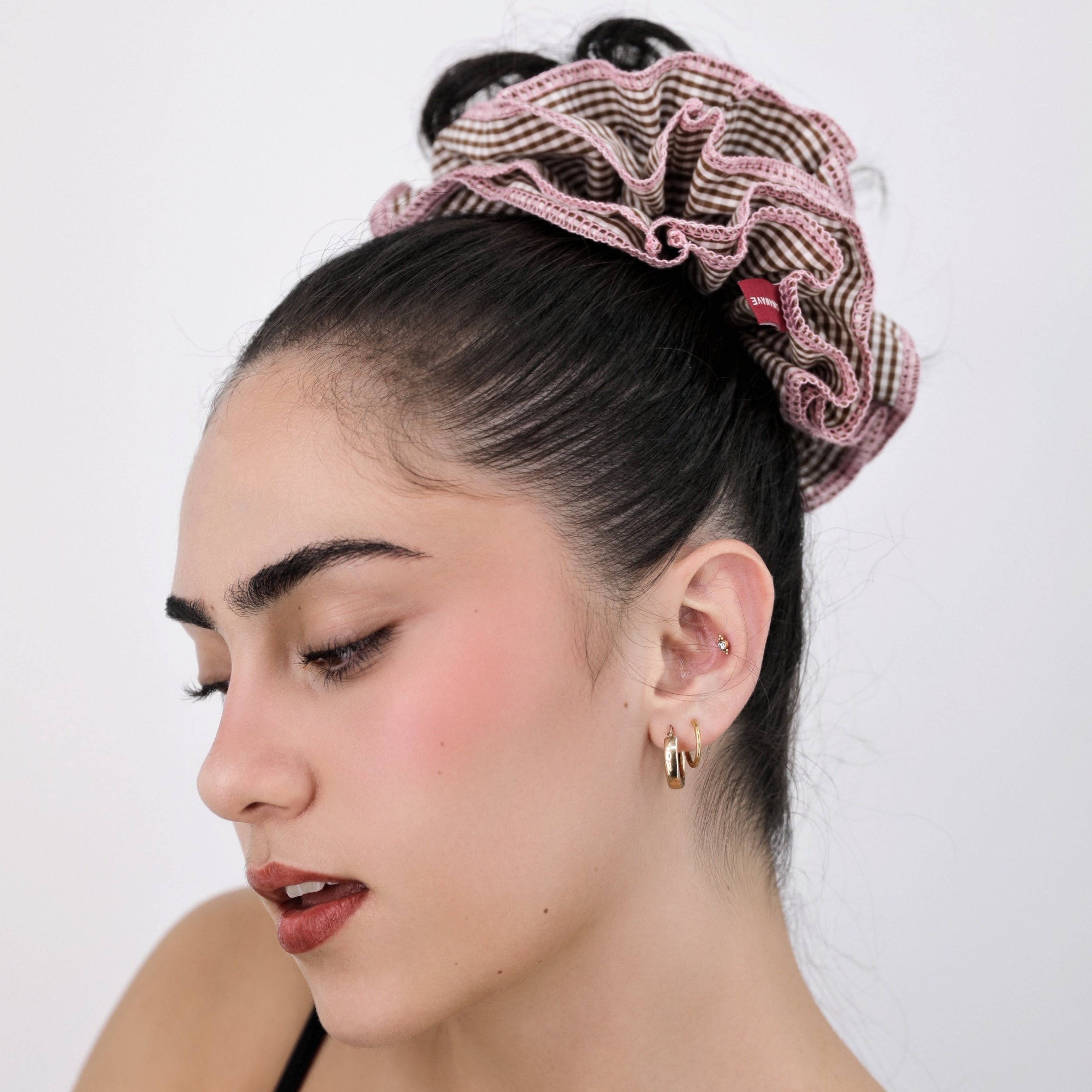 Woman wearing a Luna Wave pink check scrunchie against a white background