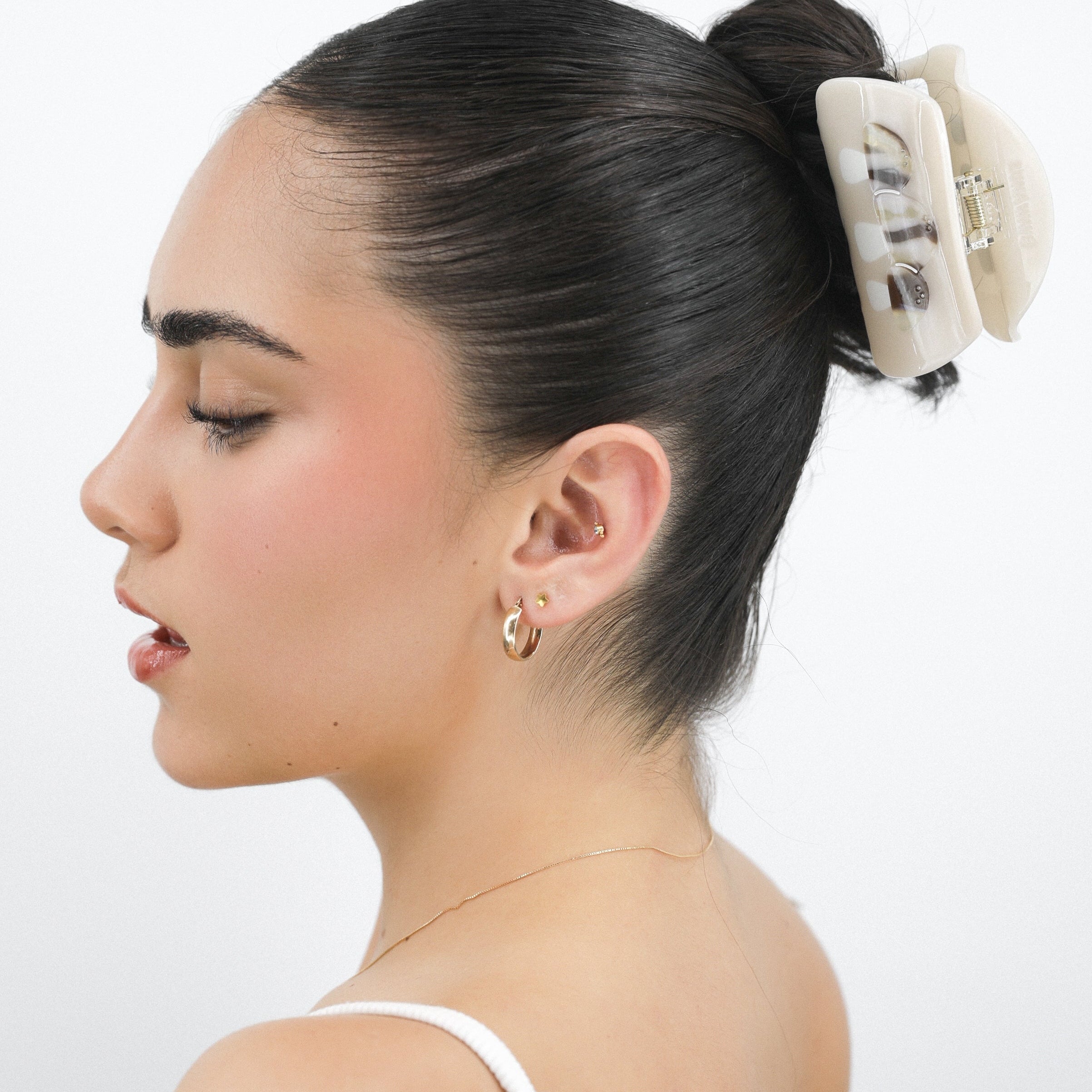 Woman with hair styled in a bun with a Luna Wave white creamy hair claw clip accessory against a white background