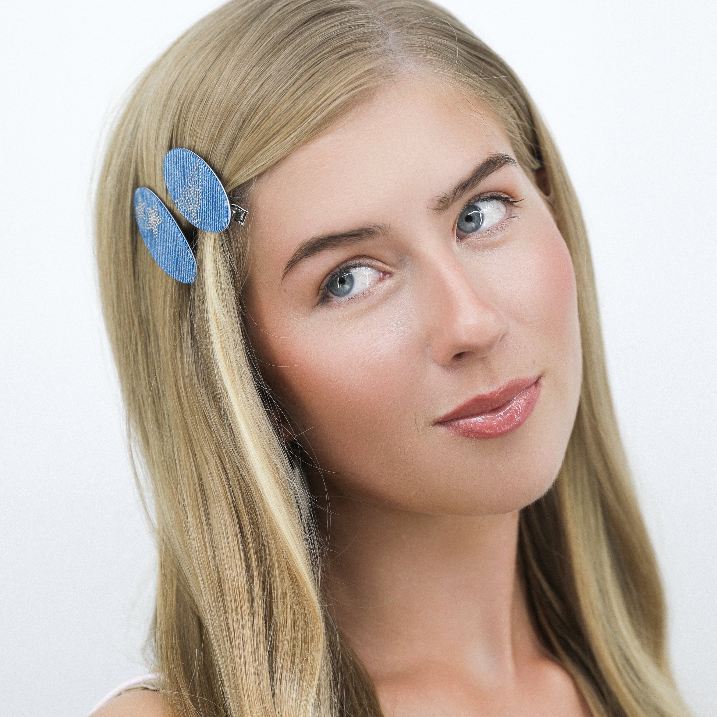 Woman with long blonde hair wearing a Luna Wave blue denim hair clips against a white background