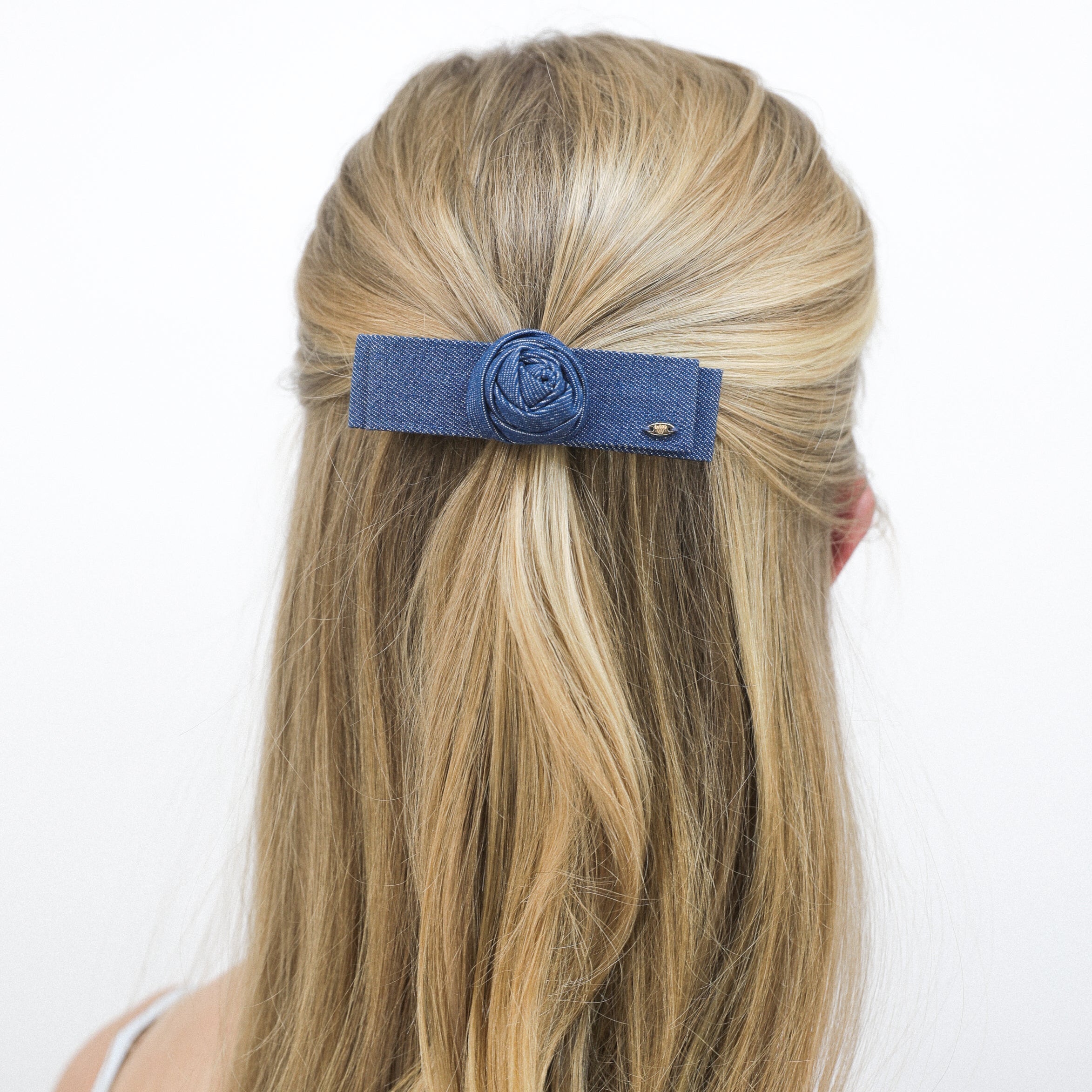 Woman with long blonde hair wearing a Luna Wave blue jean denim rose hair barrette on a white background