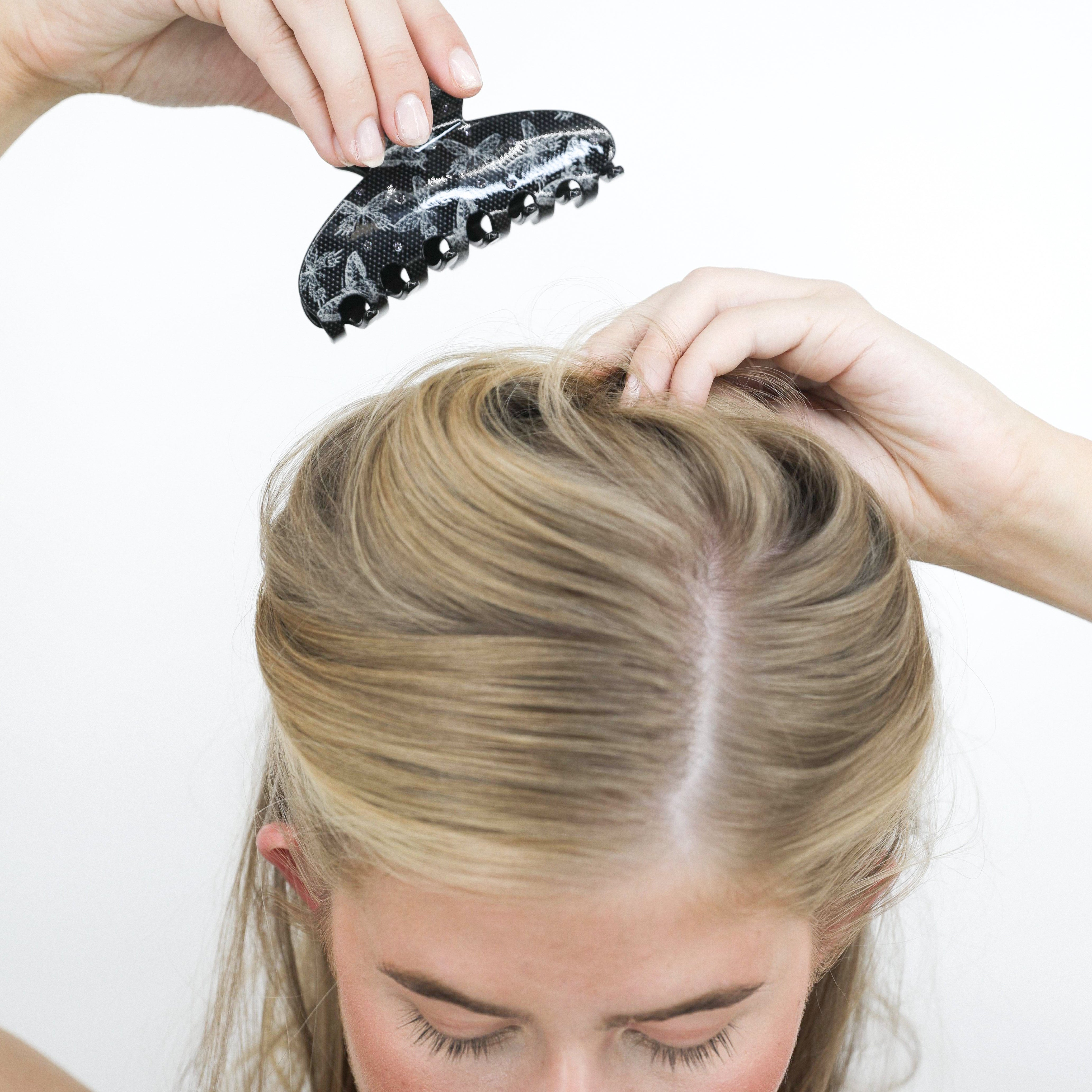 Woman using a Luna Wave flatter black hair claw clip on her blonde hair against a white background