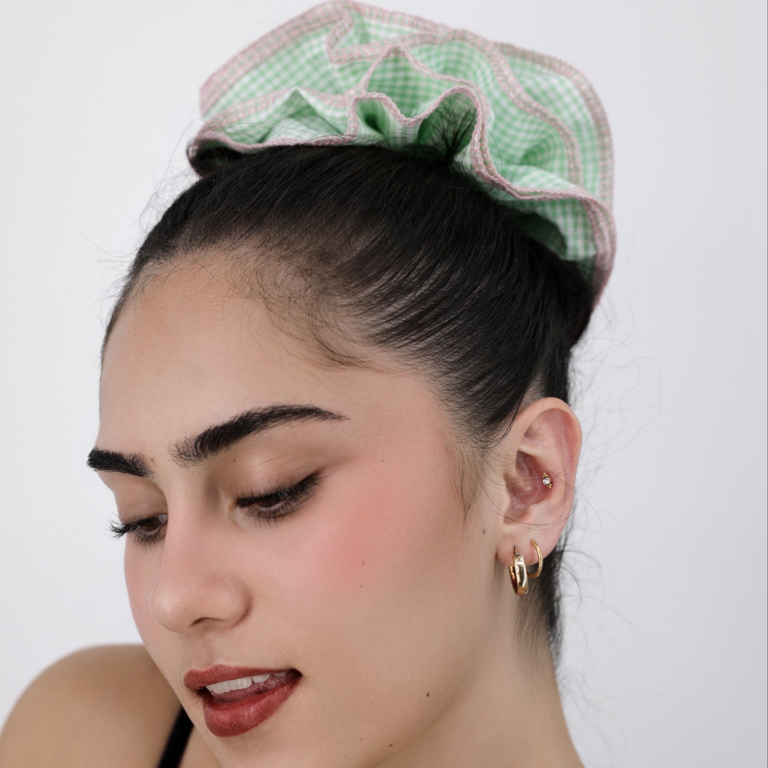 Woman wearing a Luna Wave green check scrunchie against a white background
