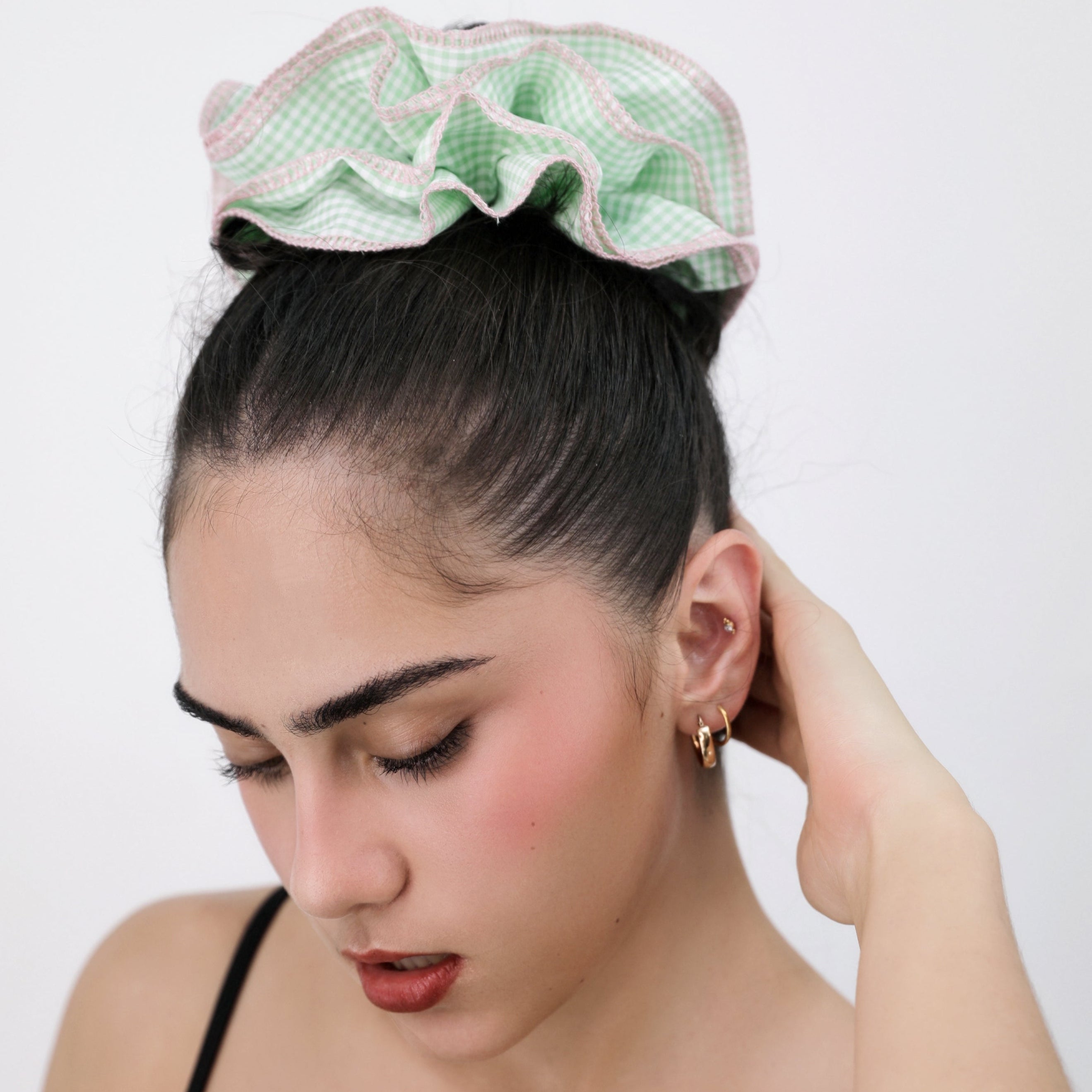 Woman wearing a Luna Wave green check scrunchie against a plain background