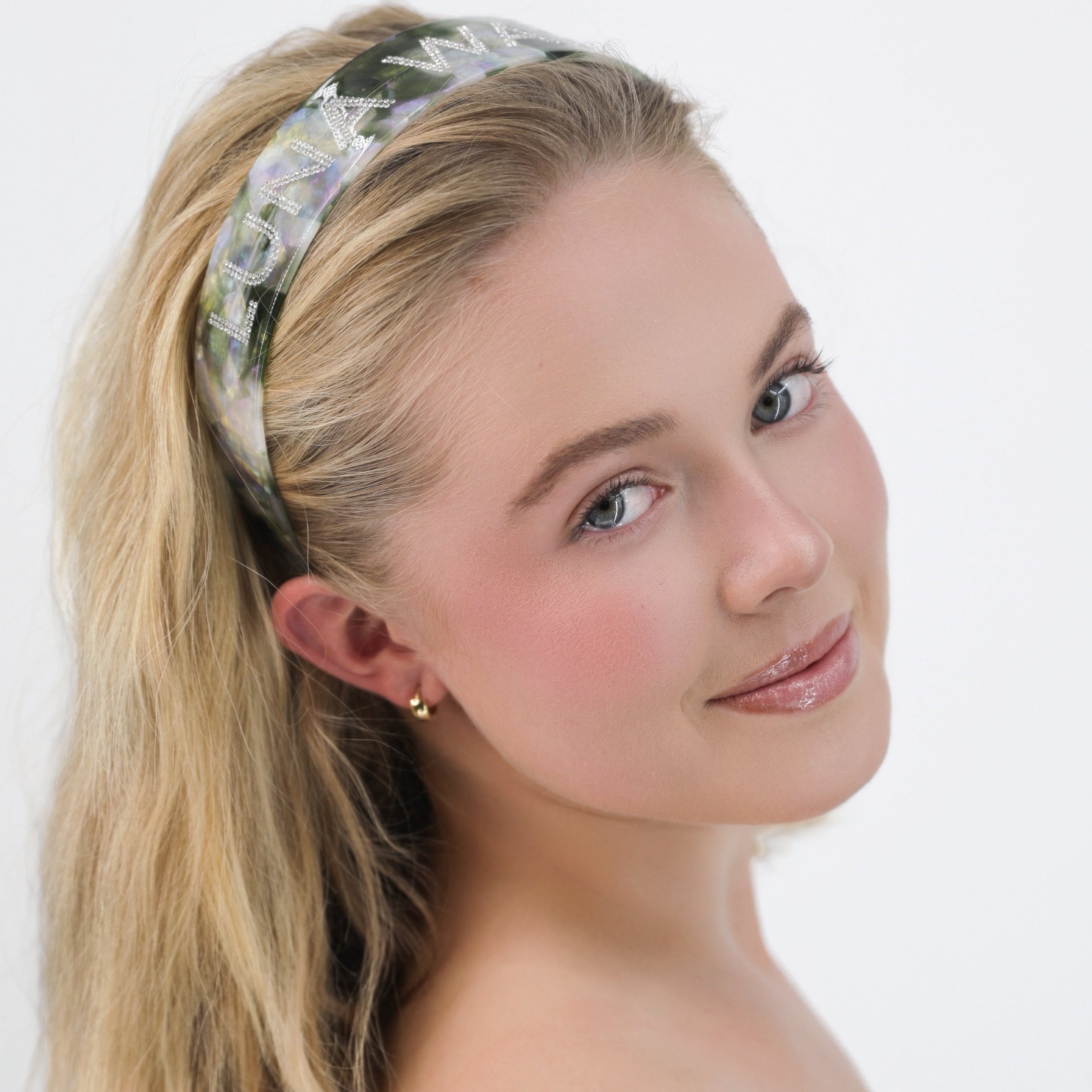 Woman wearing a Luna Wave green emerald signature hair headband with a plain background