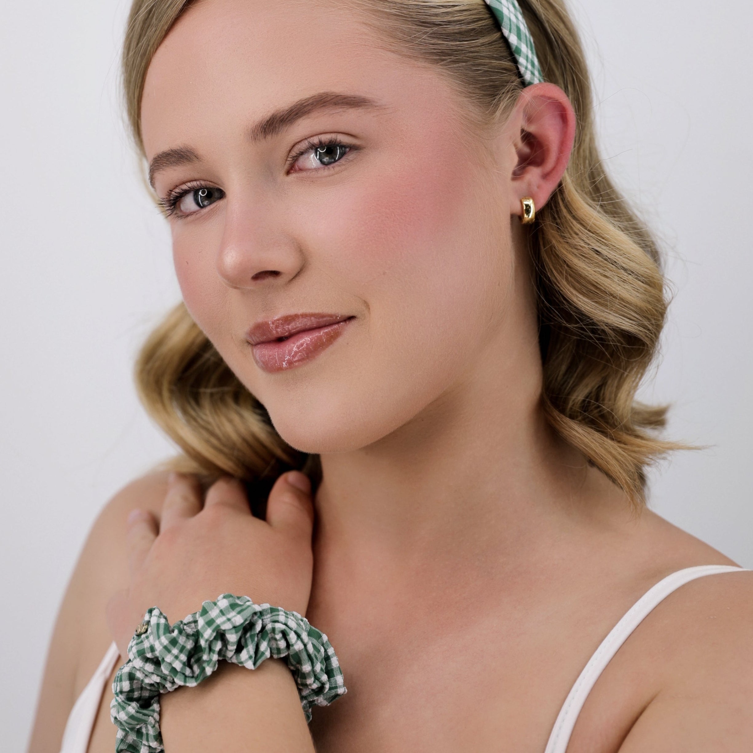 Woman wearing a Luna Wave green meadow gingham headband and scrunchie against a white background