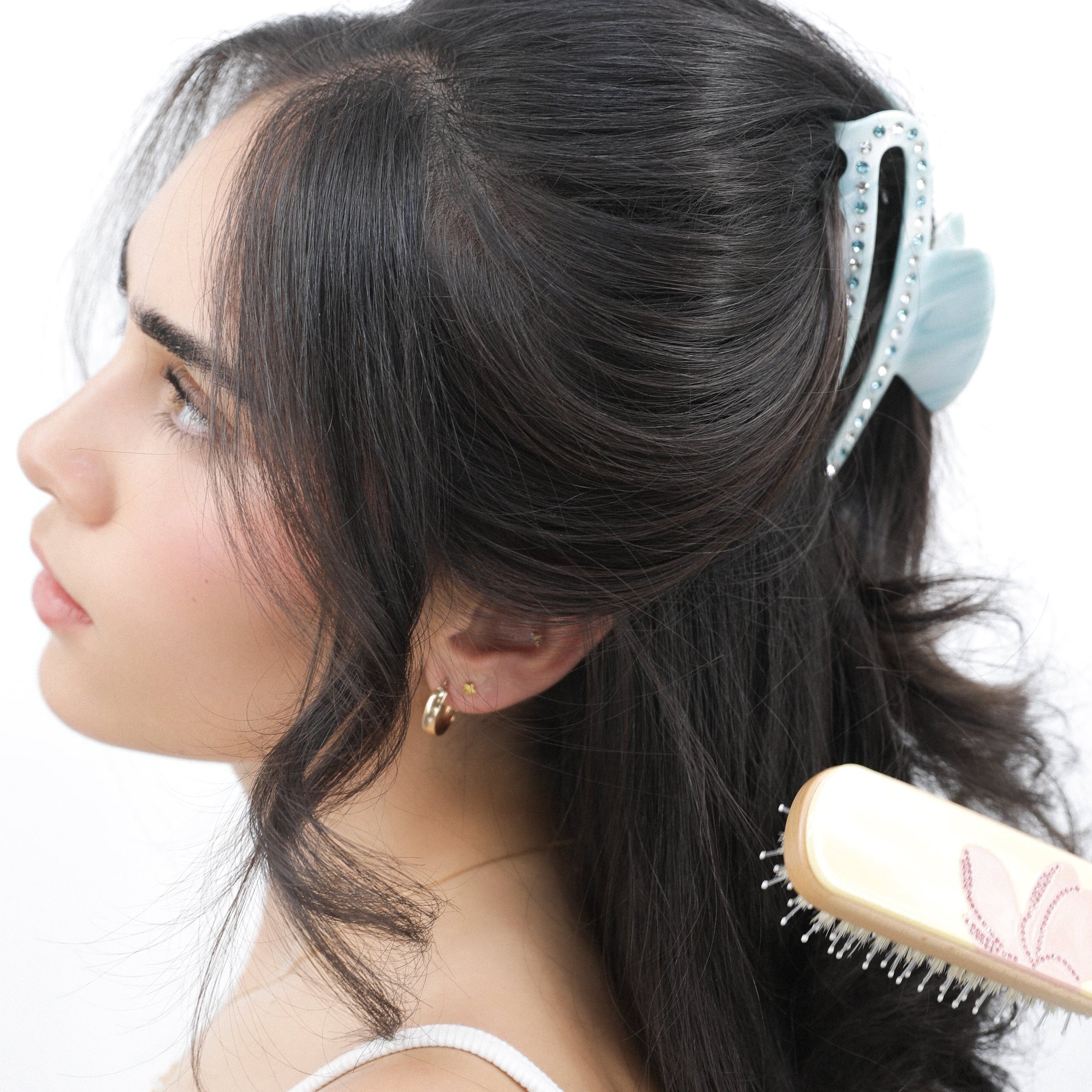 Woman brushing her hair and wearing Luna Wave blue ice cloud large hair claw clip with a white background