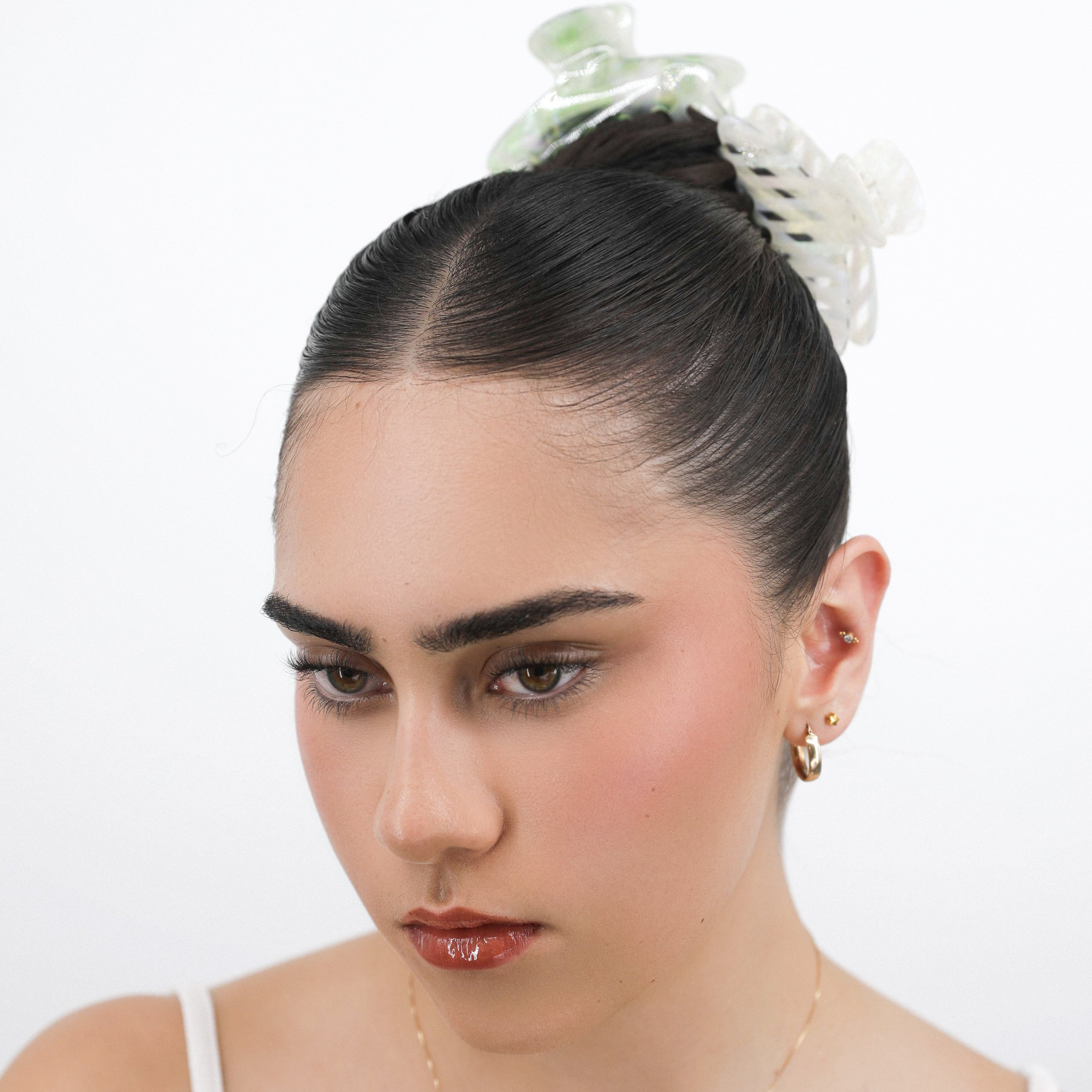Woman with styled hair with Luna Wave initial green and white hair claw clips against a white background