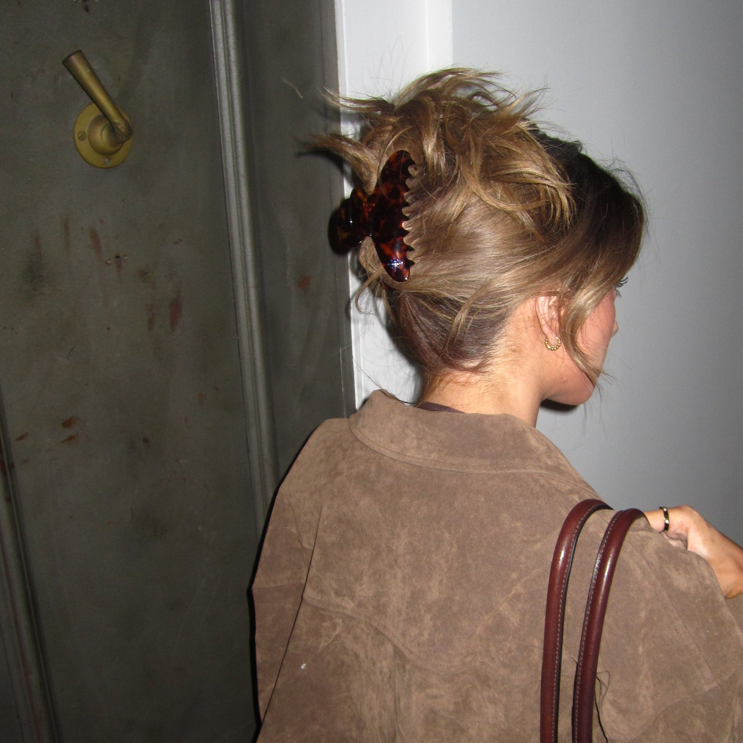 Person wearing a Luna Wave amber starlet large claw clip and hat lying on a door with a key visible.