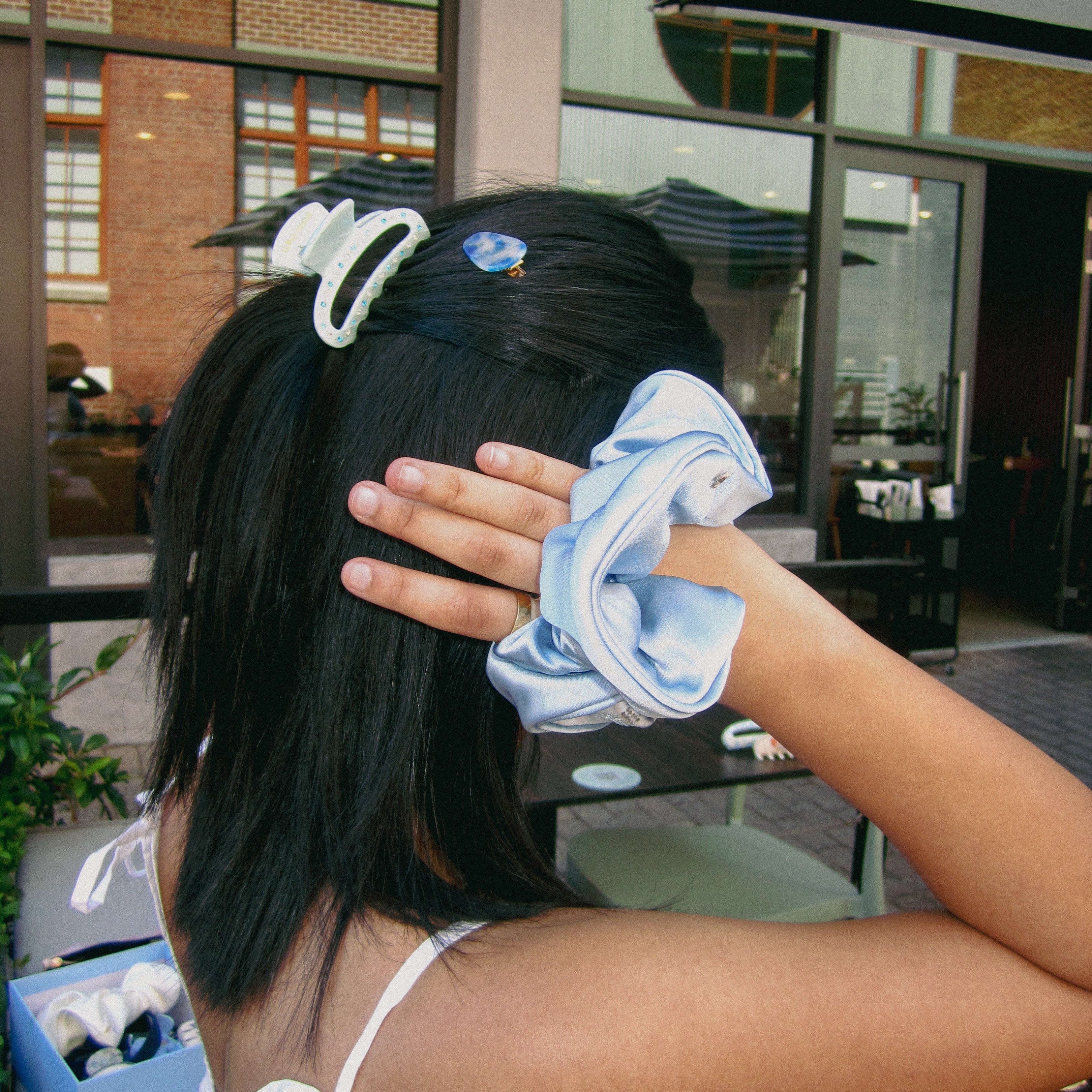 Person with hair tied back using a blue scrunchie in an outdoor setting