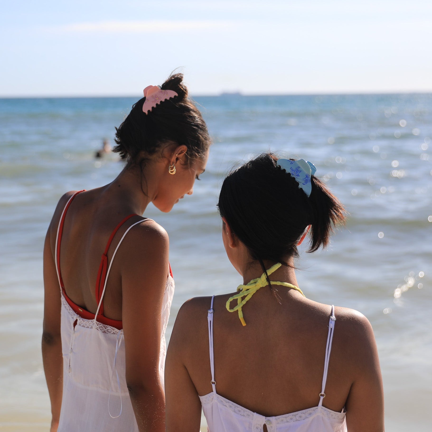 Two Luna Wave models wearing pink blue blossom claws at beach.