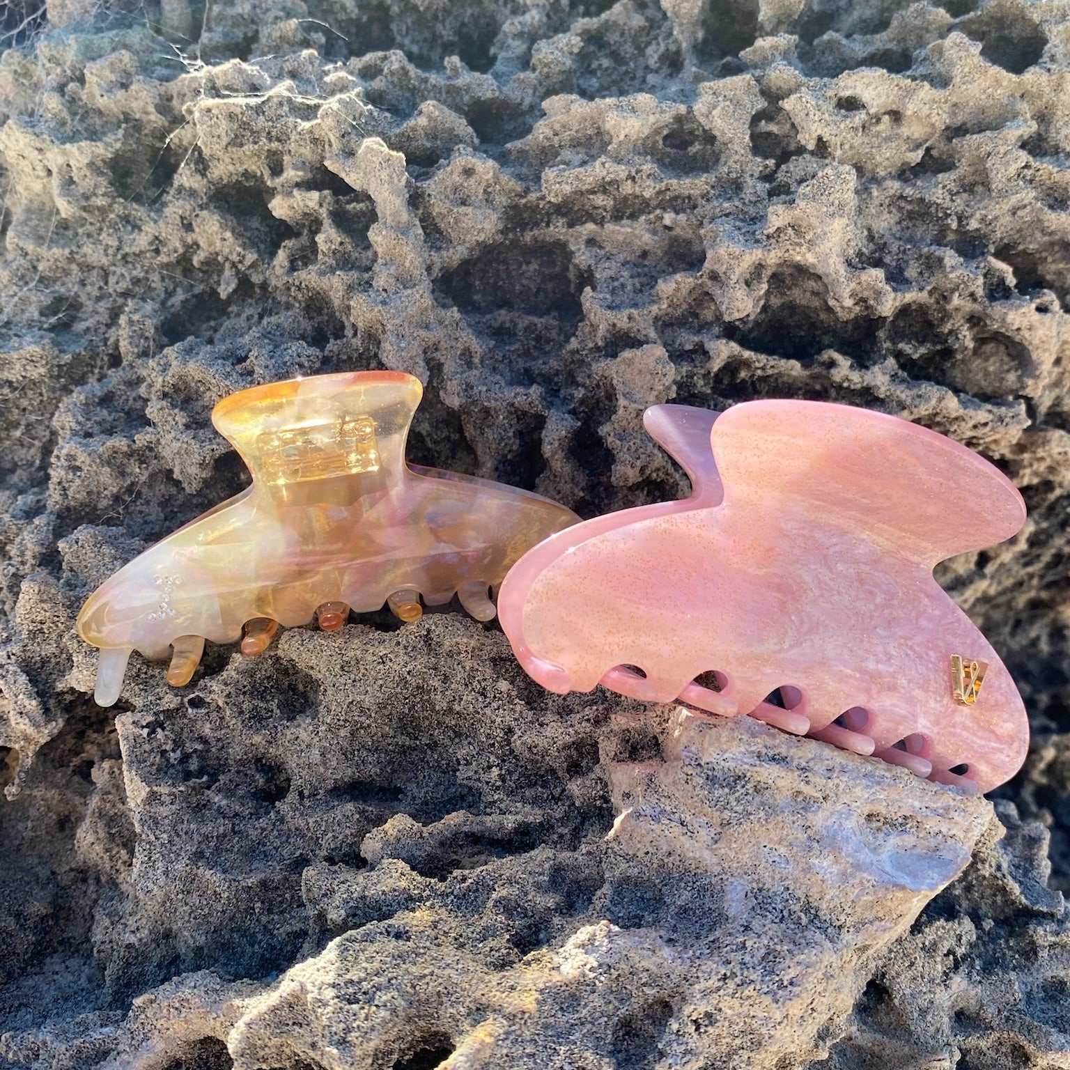 Two Luna Wave pink hair clips on a textured stone surface