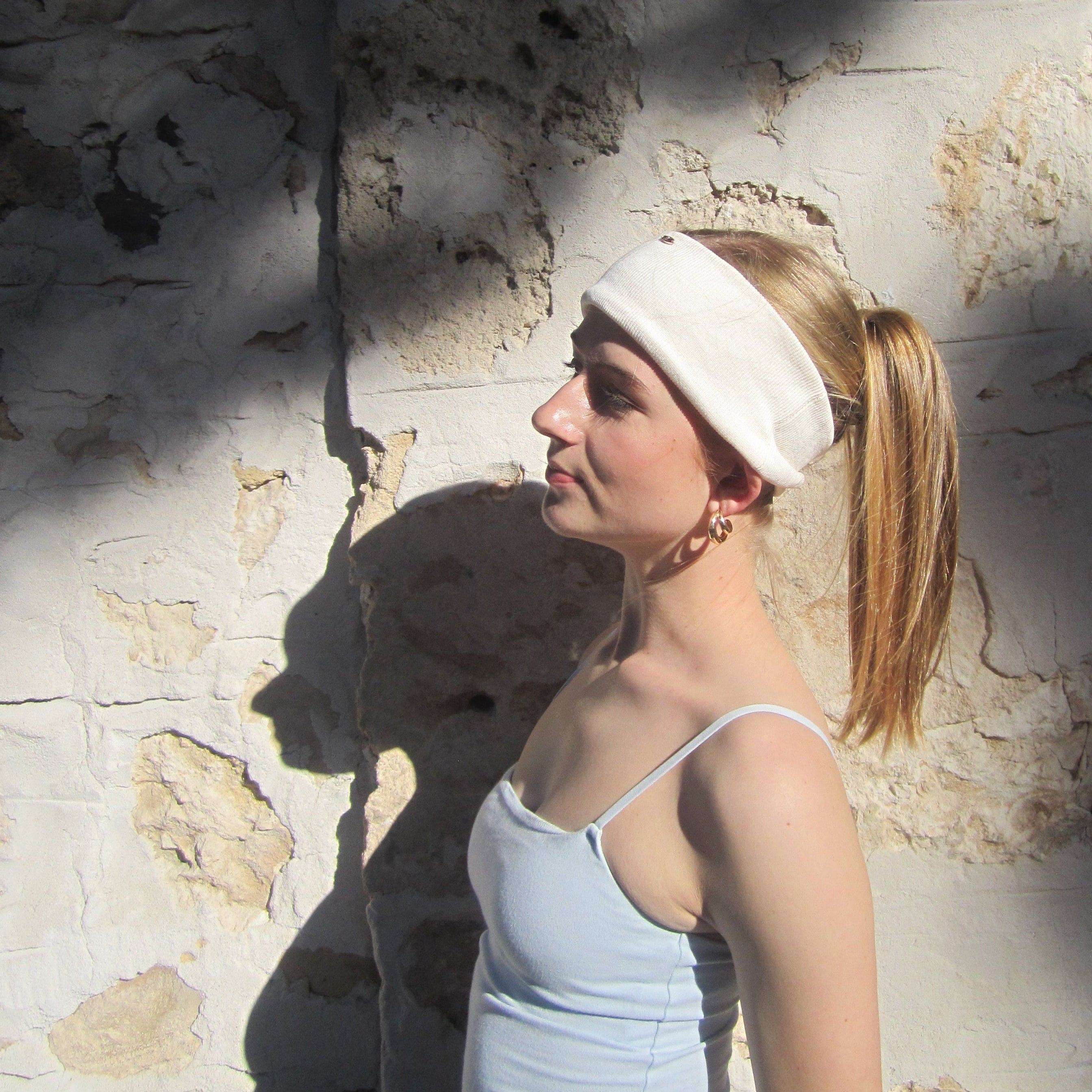 Luna wave model stretching on a stone wall with a creamy soft headband