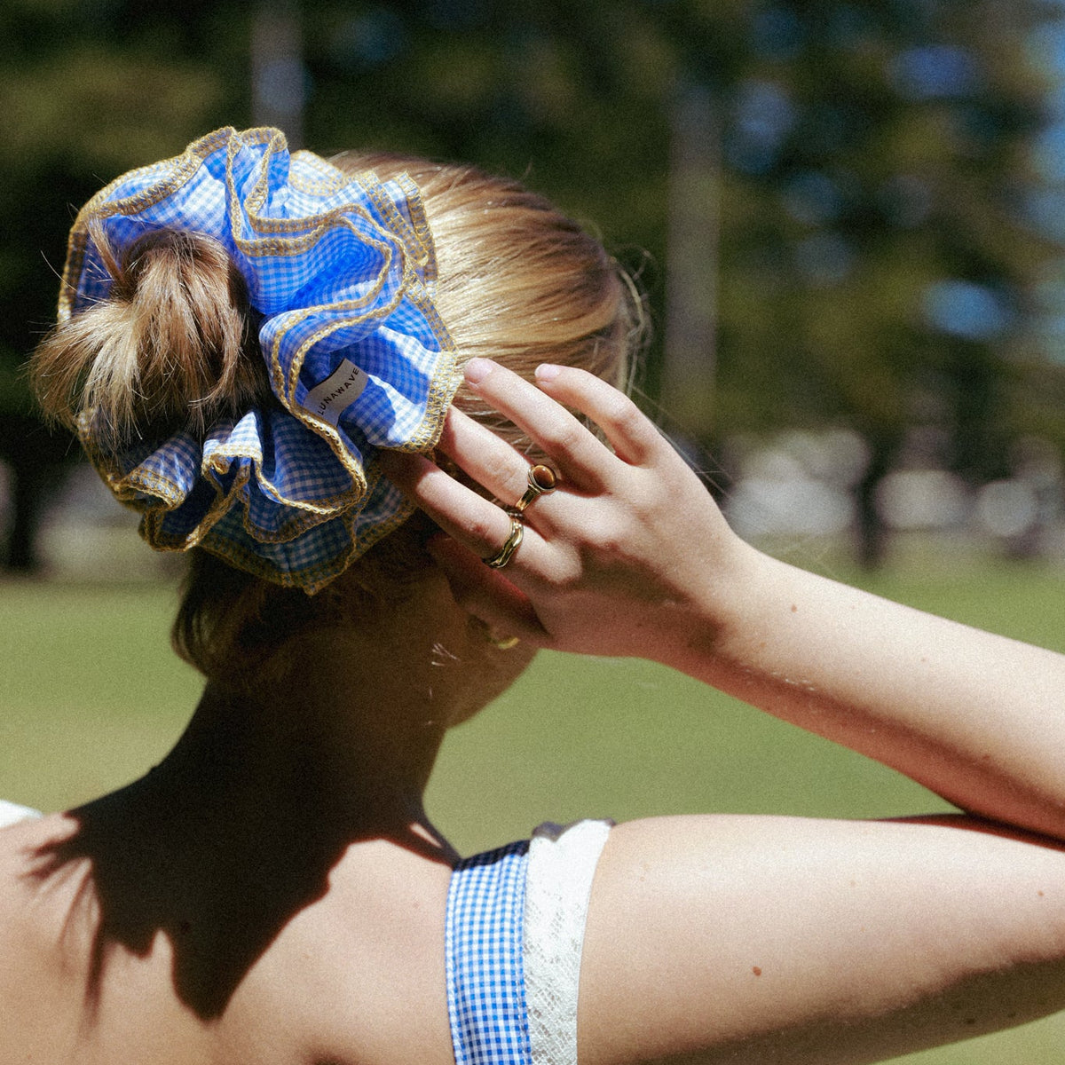 Woman with a blue and white checkered scrunchie in an outdoor setting