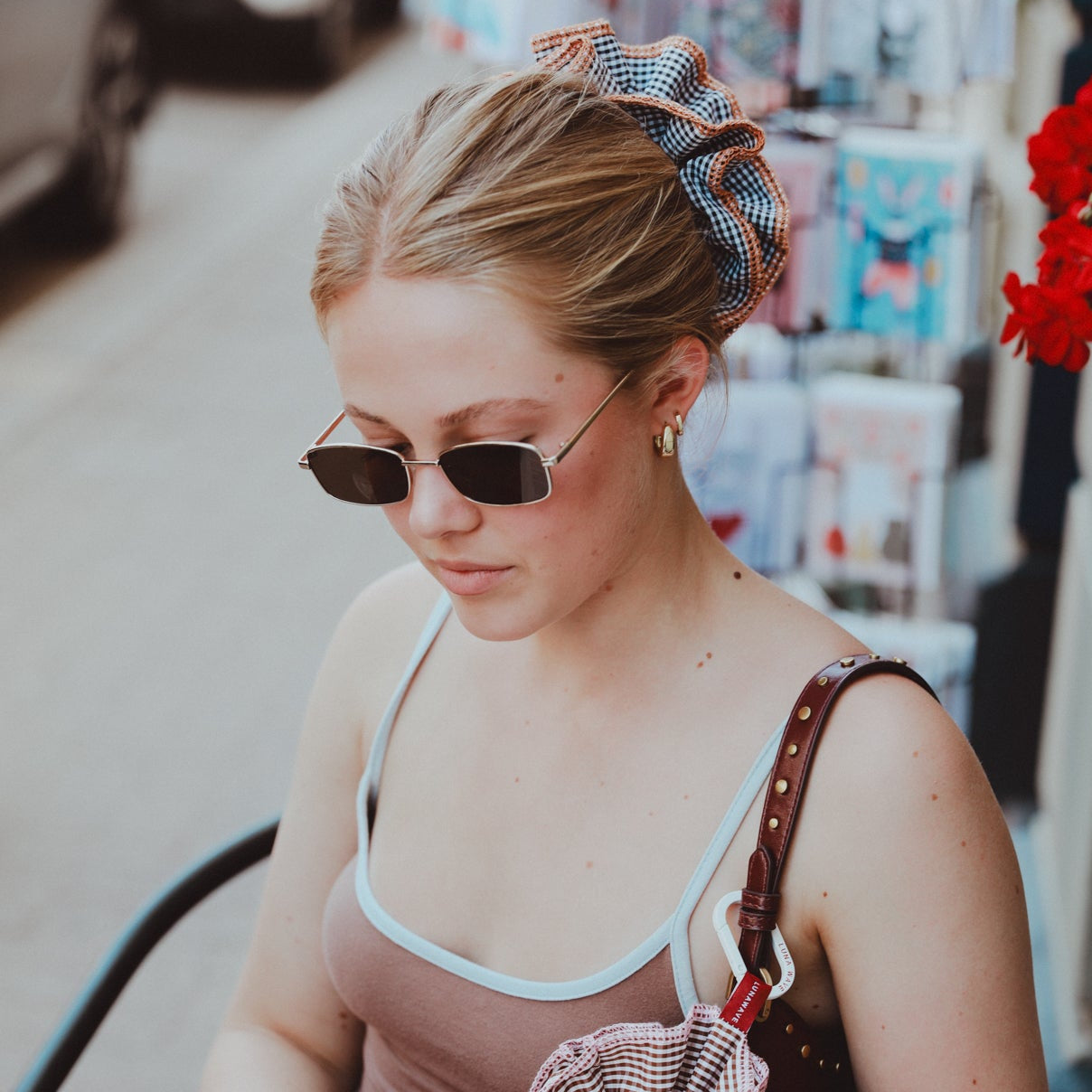 Woman reading a book in a store with sunglasses and a bow in her hair