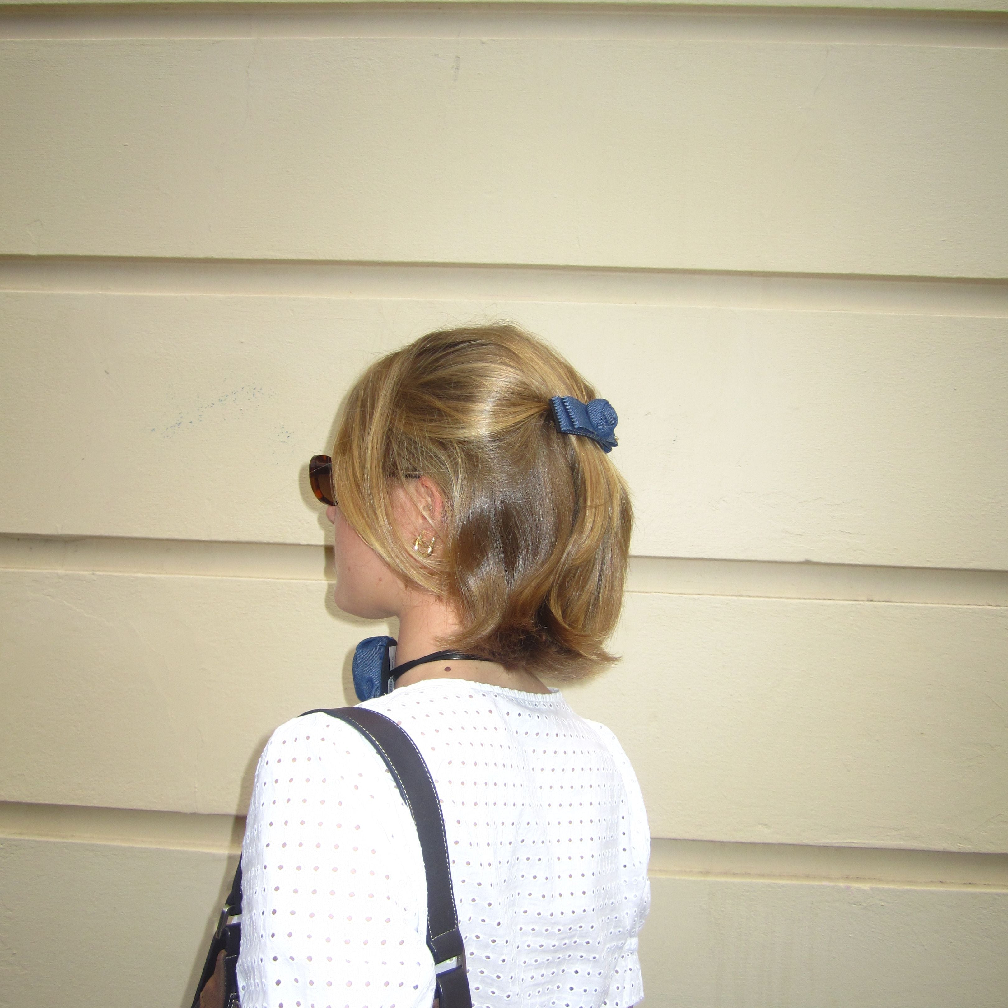 Person wearing a white shirt with a luna wave denim rose barrette