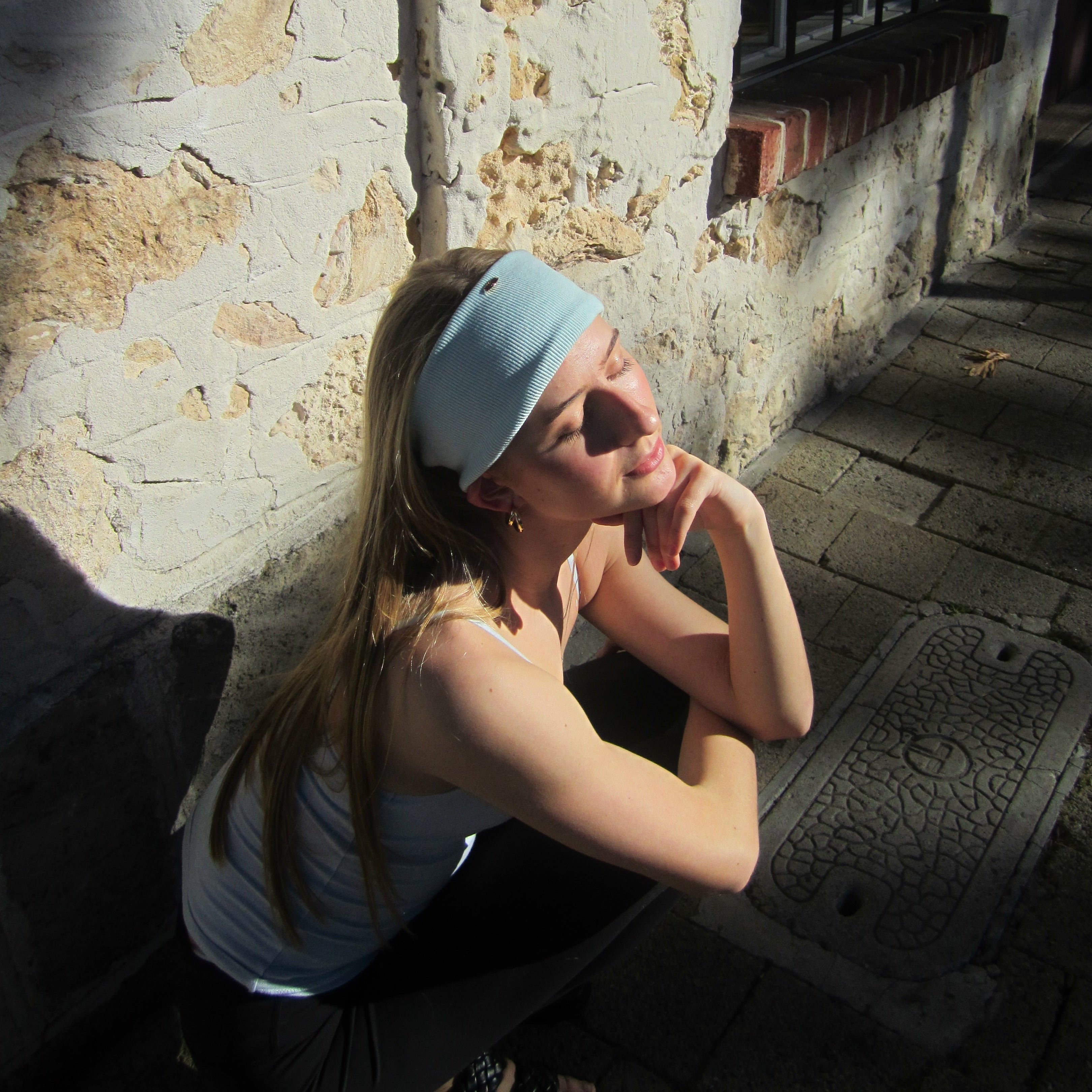 Luna wave model sitting against a stone wall with a blue ice soft headband