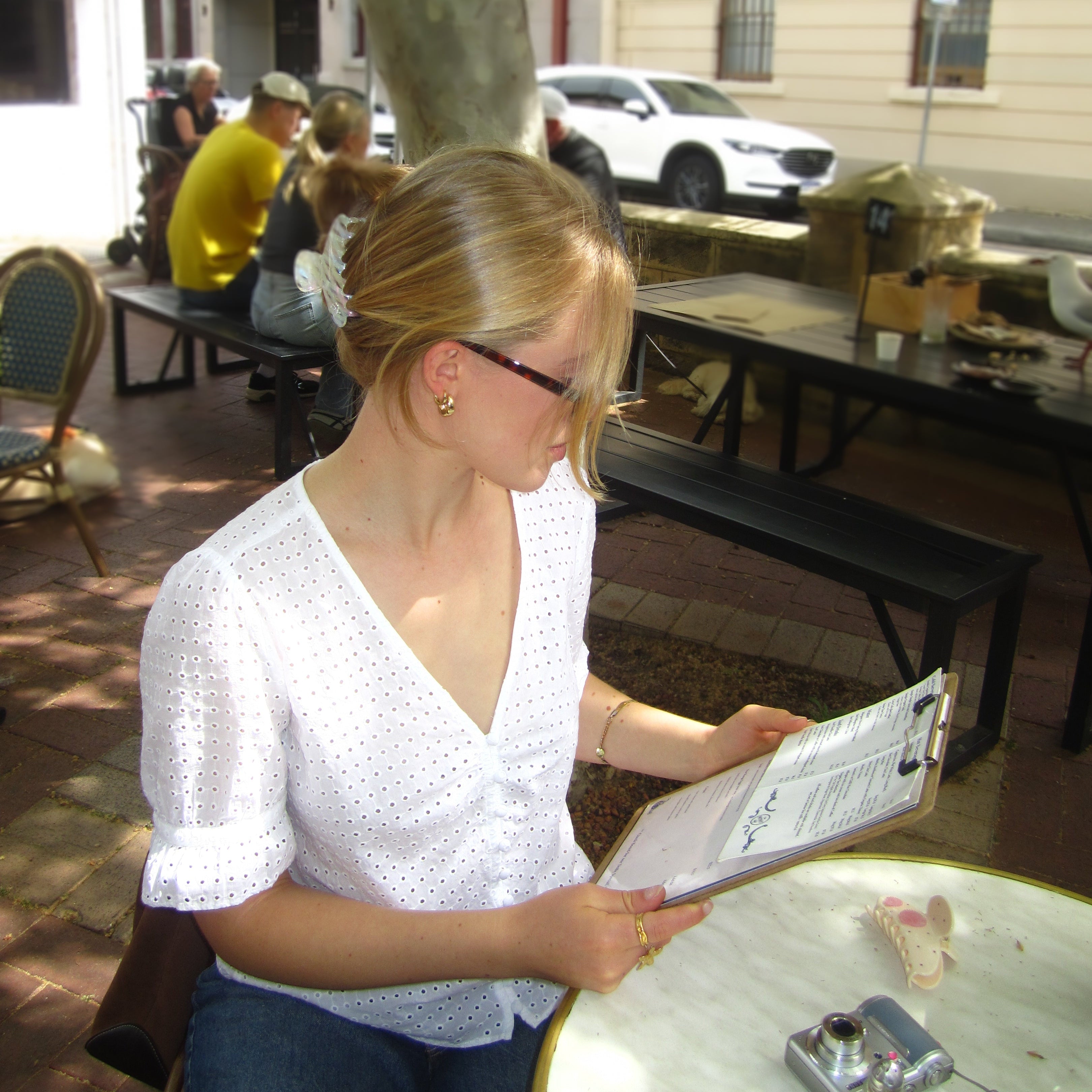 Woman wearing Luna Wave initia claw clip reading a menu outdoors with a tree 