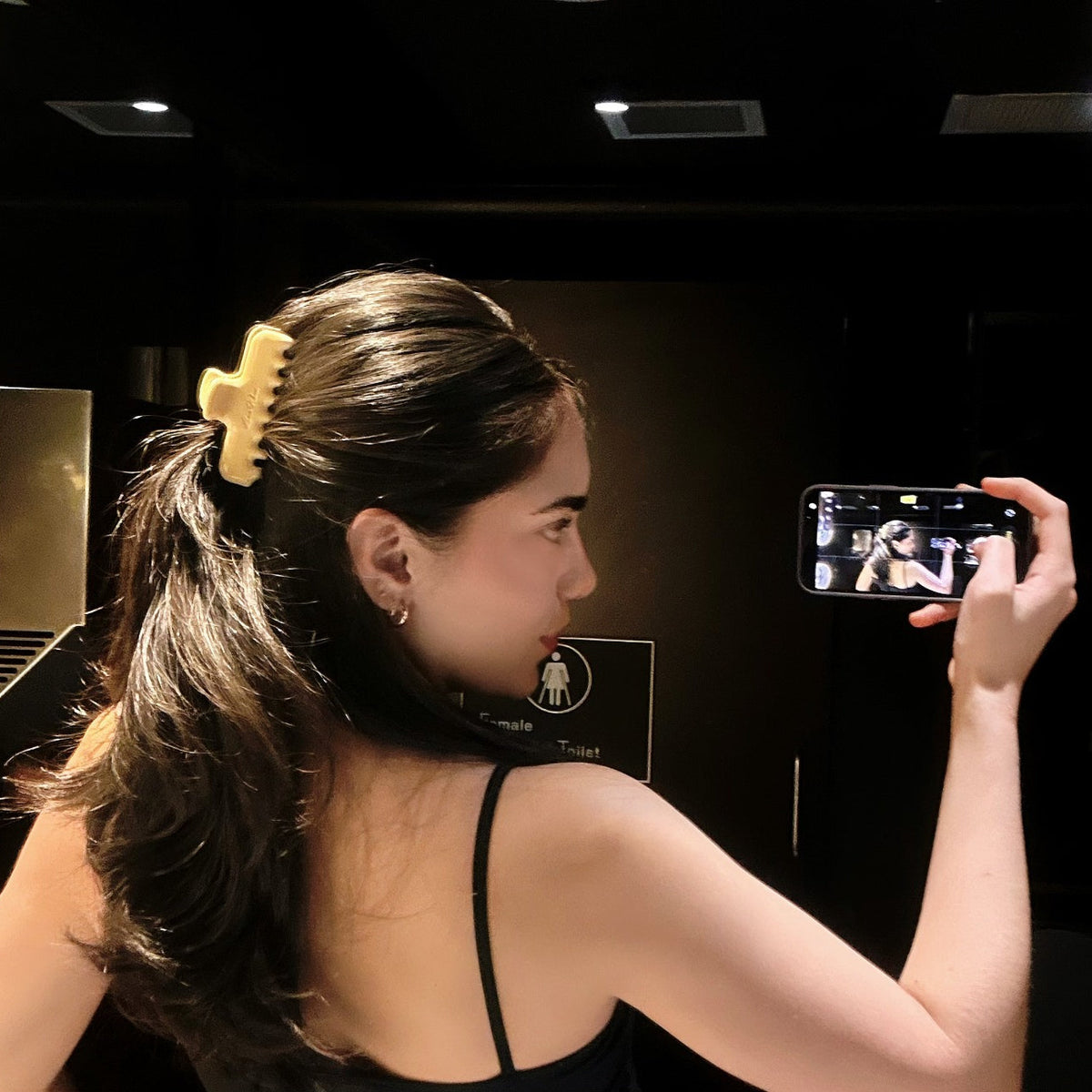 Mirror side profile of a model wearing Luna Wave Jelly Claw in Butter in a half up hairstyle.