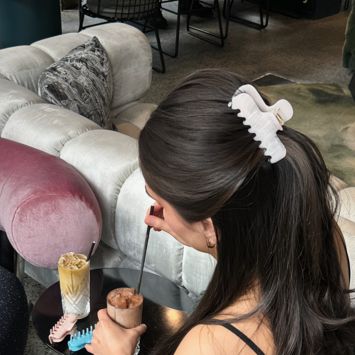 Model wearing the pale pink Luna Wave Jelly Claw in Blush in a half up hairstyle while seated with ice cream.