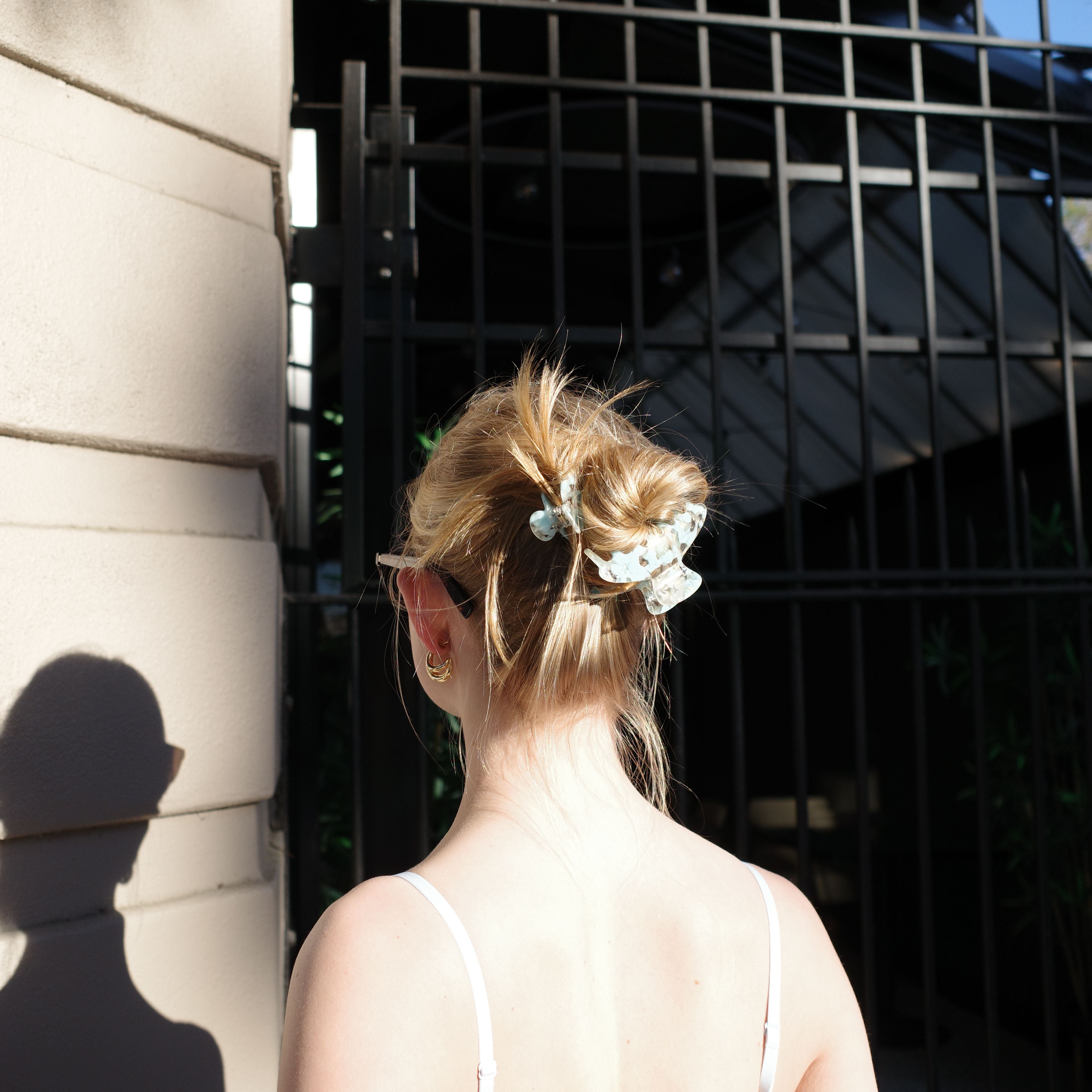 Luna Wave lady in a white dress with a mist flora claw clip in front of door