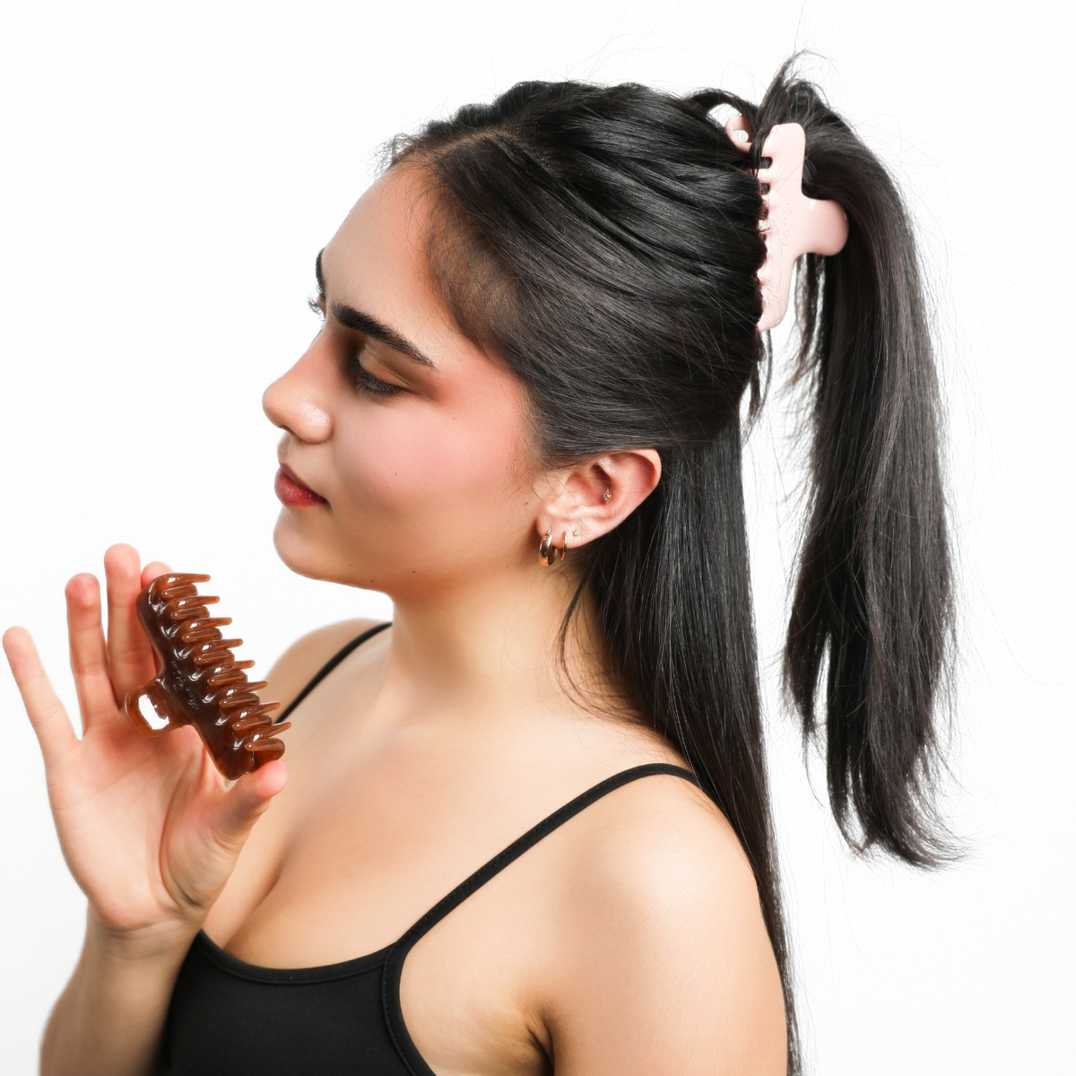 Model wearing the pink Luna Wave Jelly Claw in Rose in a high ponytail while holding a brown claw clip.