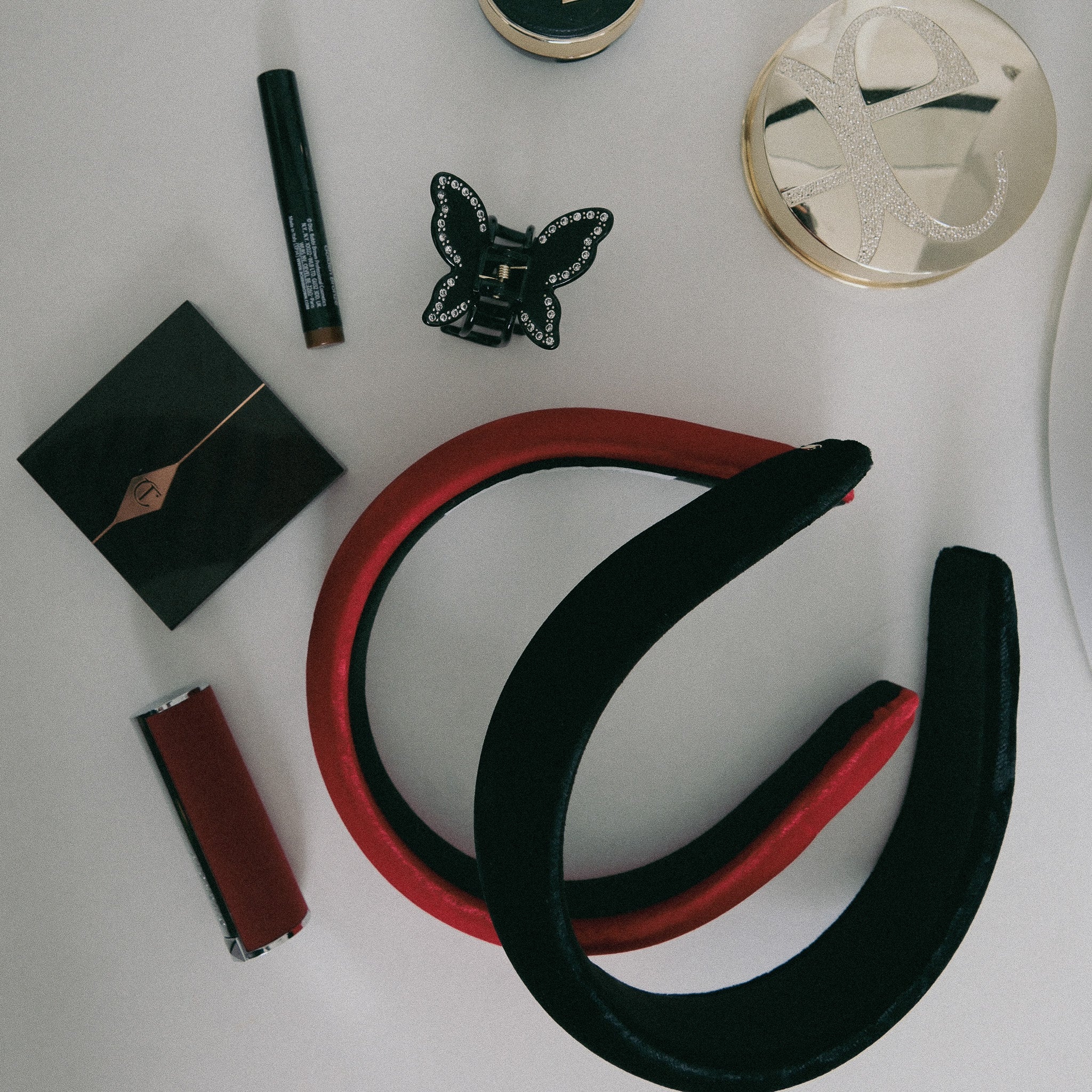 Luna Wave black and red velvet headband , Luna Wave butterfly claw with makeup items on a white surface