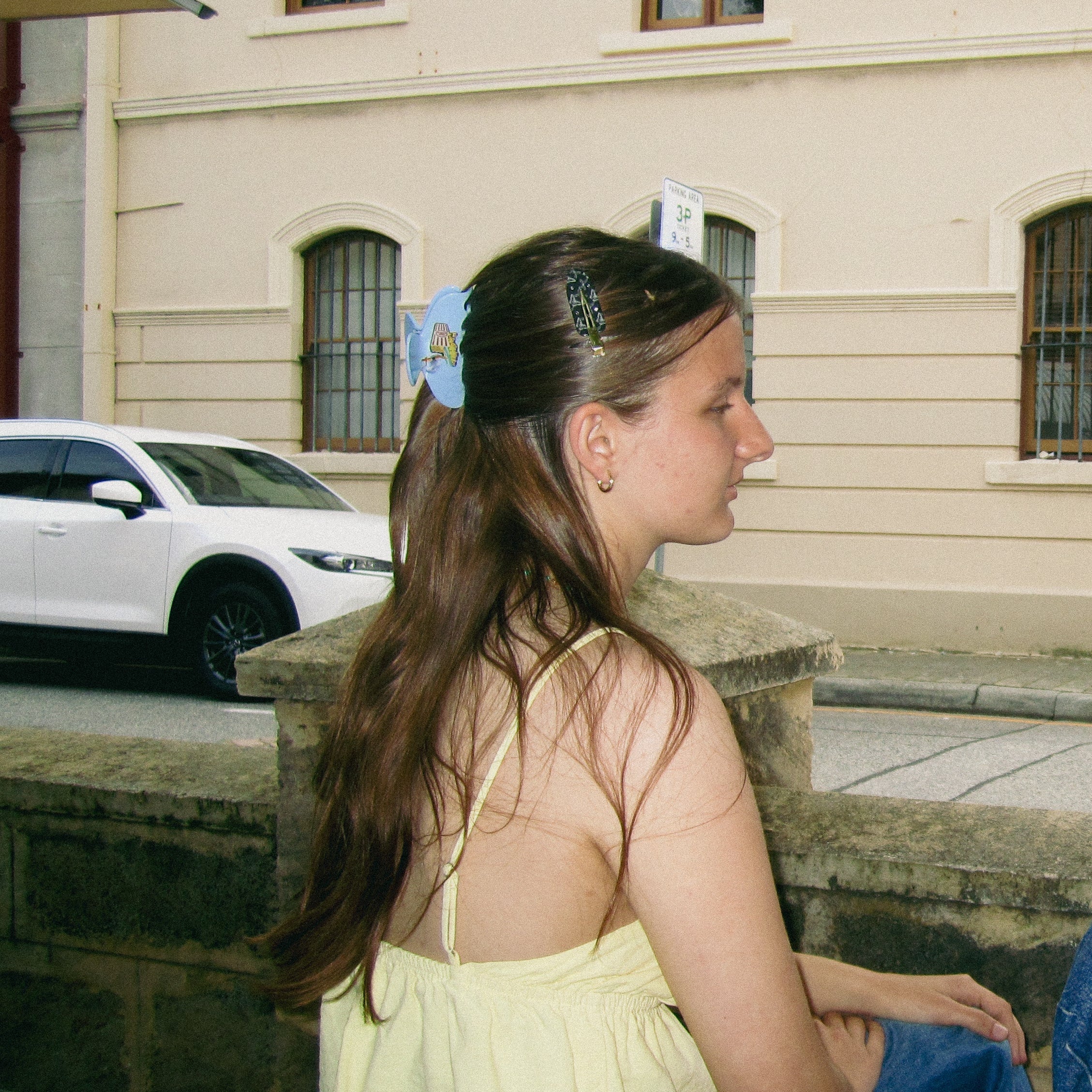 Woman wearing a vintage claw sitting outdoors with a building in the background