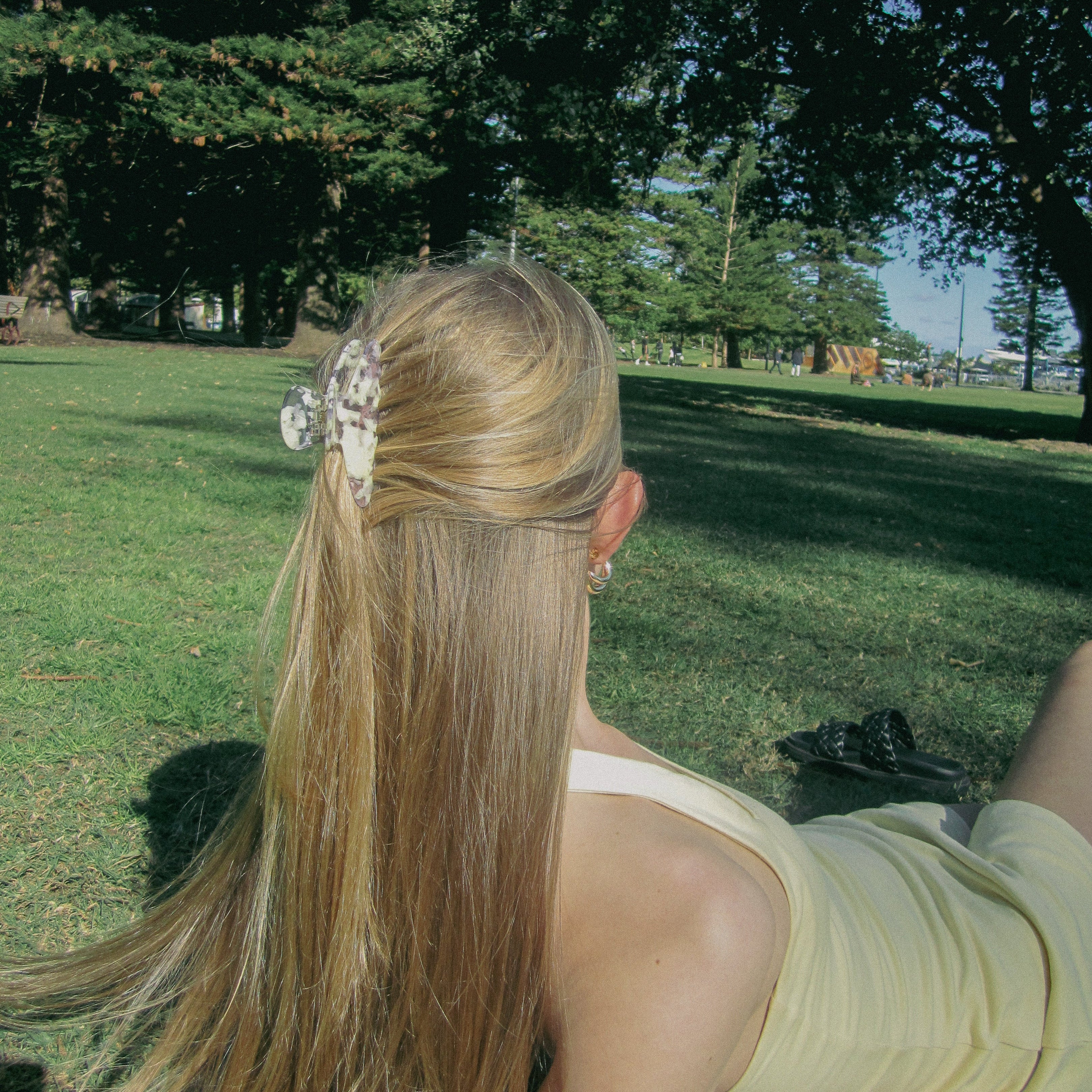 Luna Wave model wearing a violet flora  claw clip styled in a low bun at an outdoor café